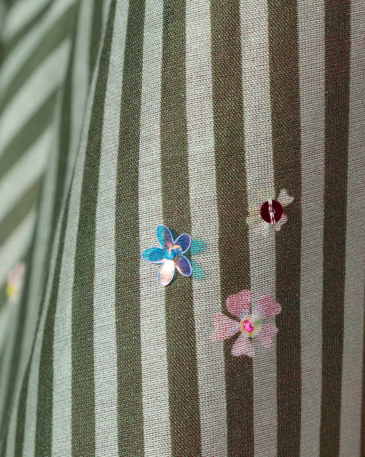 Close-up of green striped Kutch kurta fabric with sequin floral embellishments.