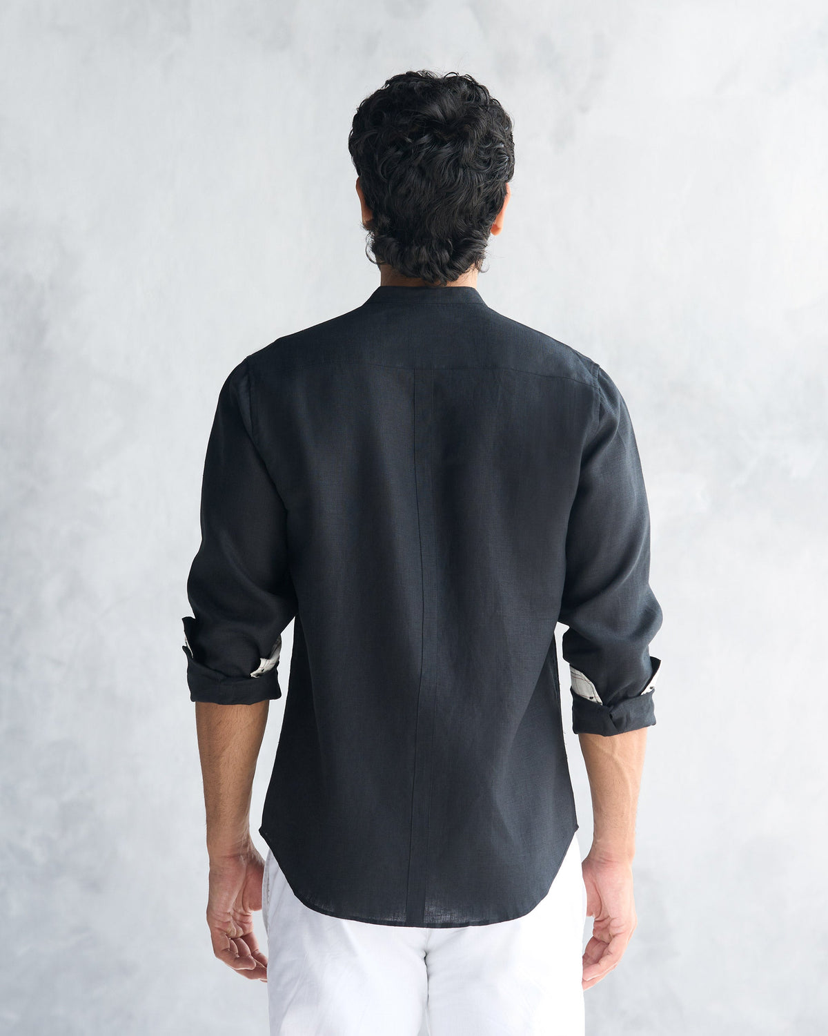 Back of a black Nawab Shirt with a center seam and rolled sleeves.