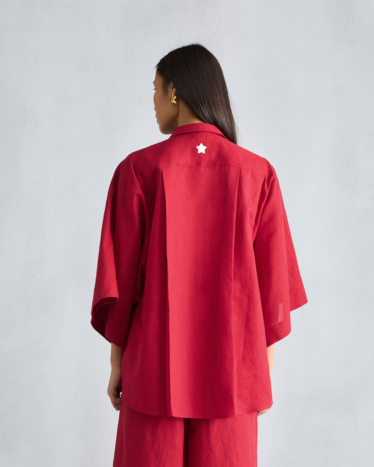 Back of the red Drop Armhole shirt worn by a person, with a white star on the yoke.