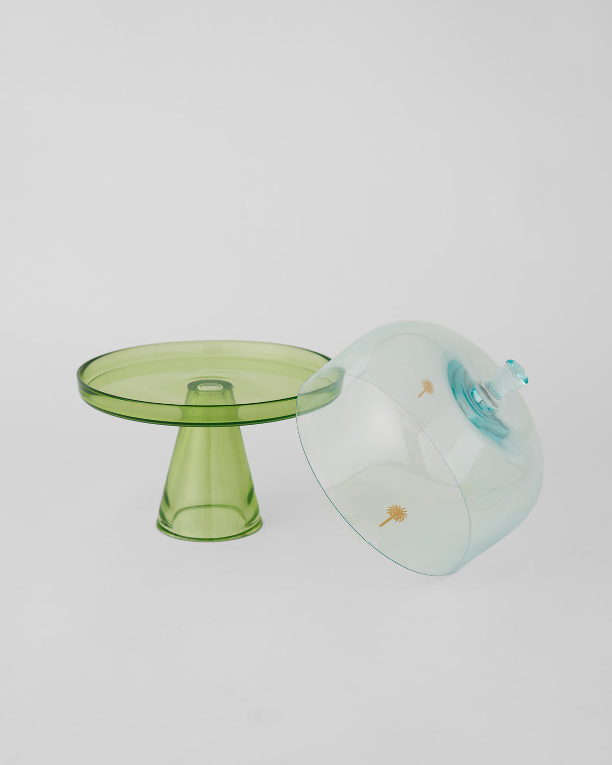 Green Vatika cake stand with its pale blue dome resting on its side.