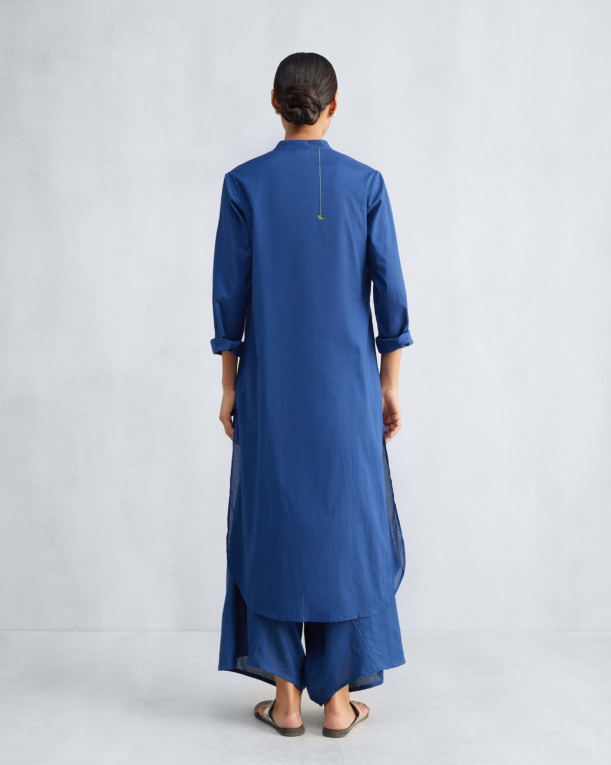 Back of a navy long kurta with a thin yellow stitch ending in a small bird motif.