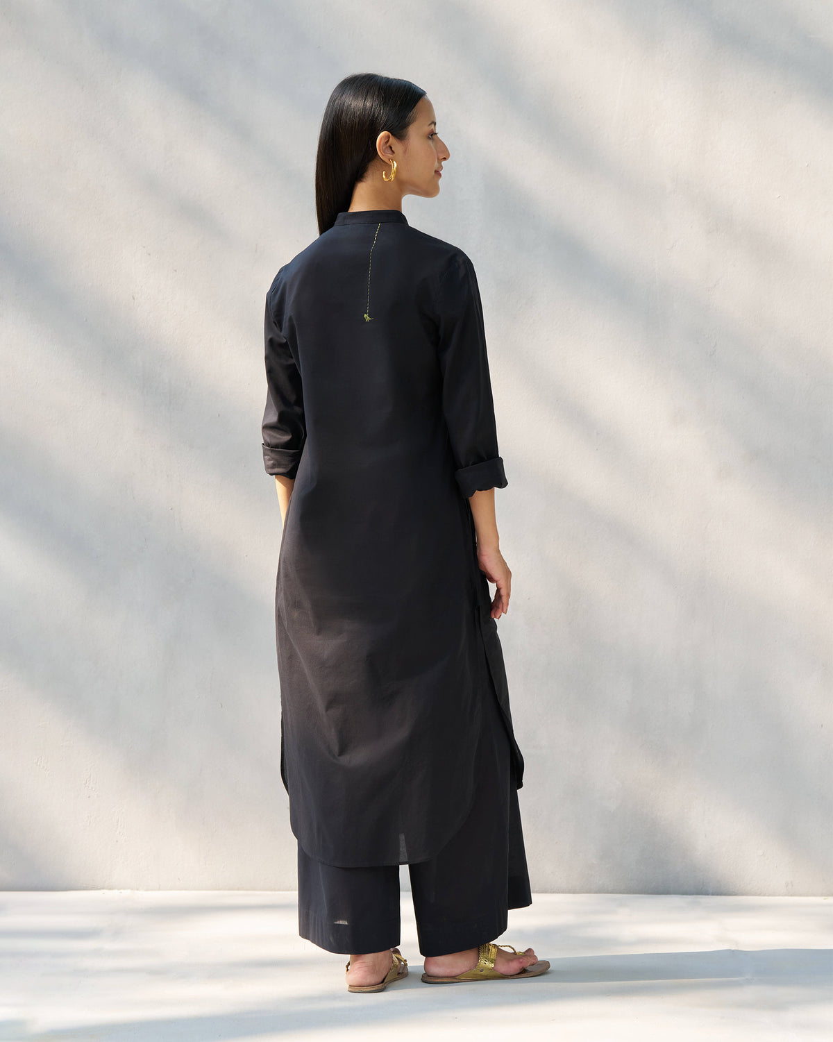 Back of a black long kurta set with a gold back detail.