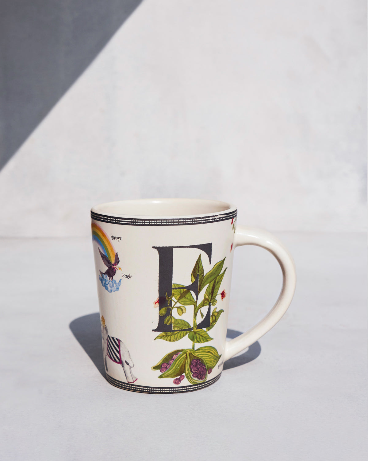 Cream Elaichi mug with a black E and green cardamom leaves.