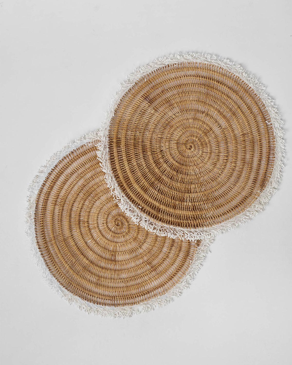 Two Kaveri Placemats overlapping, showing the round woven pattern.