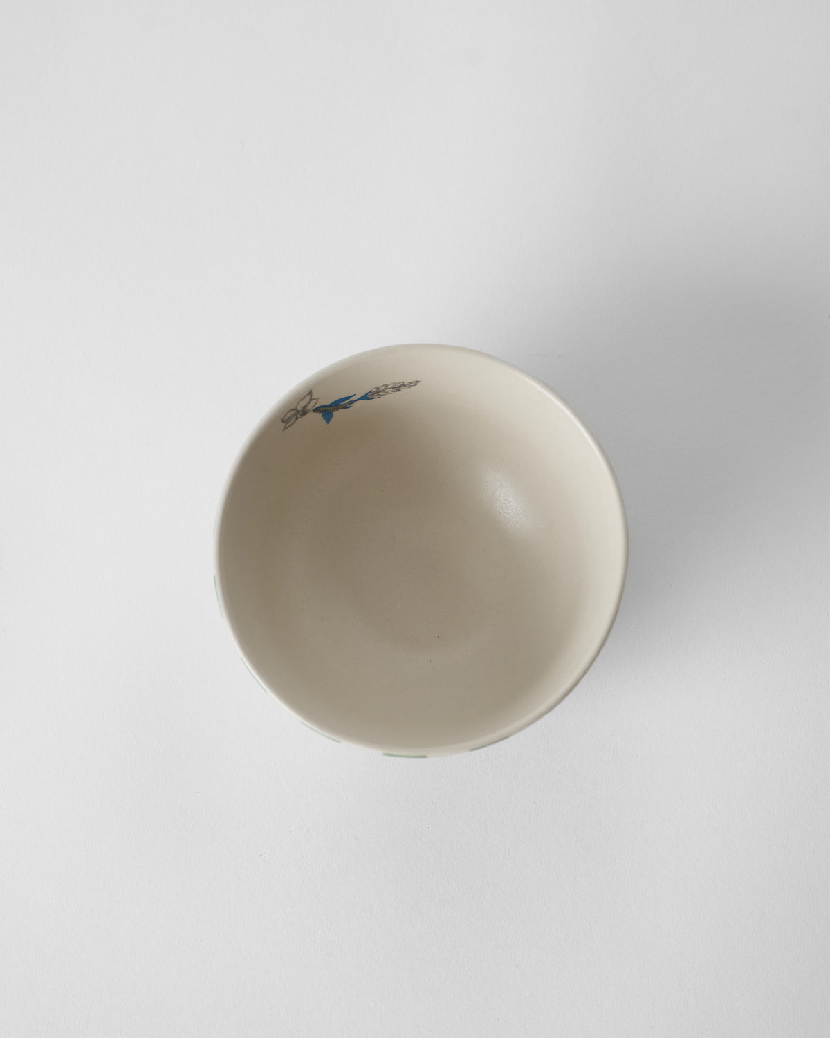 Overhead view of a cream Reesha katori with a blue bird motif on the rim.