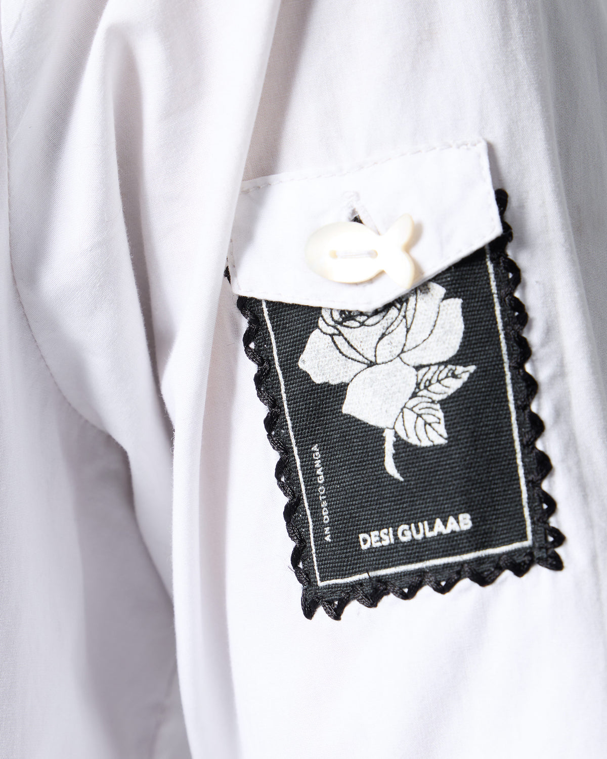 Close-up of a Desi Gulaab rose stamp patch on a white shirt sleeve.
