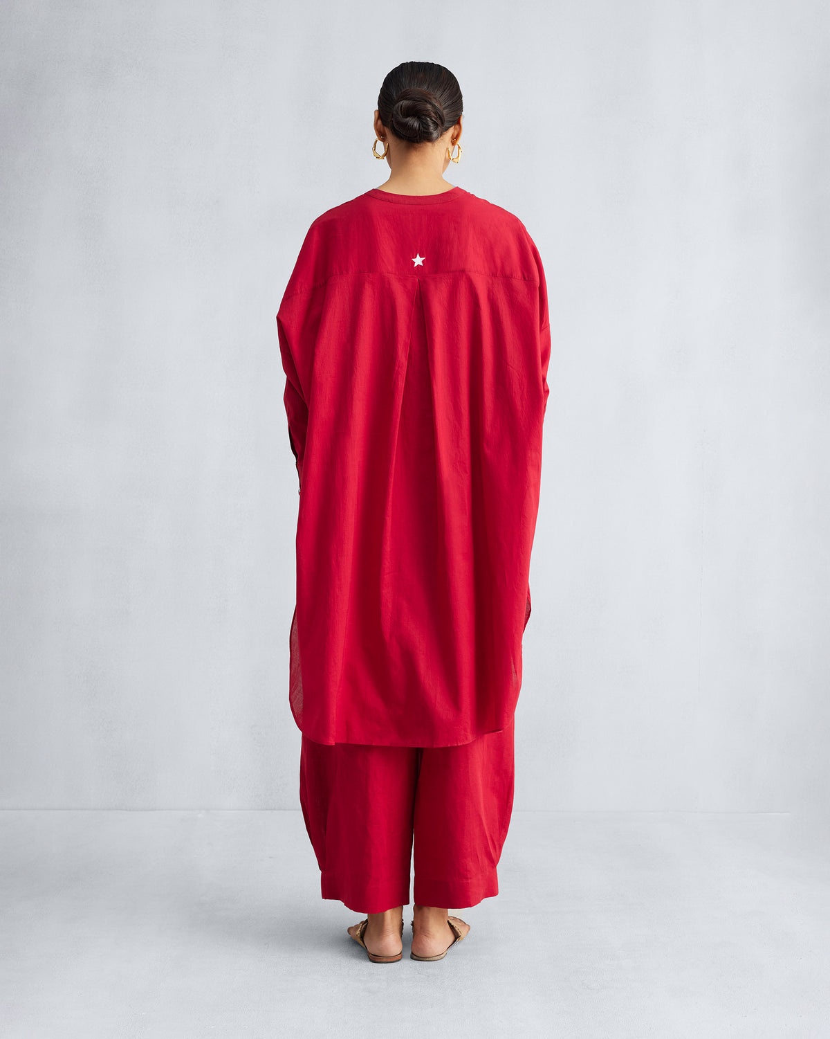 Back of a red Lazy Sunday tunic with a white star and box pleat.