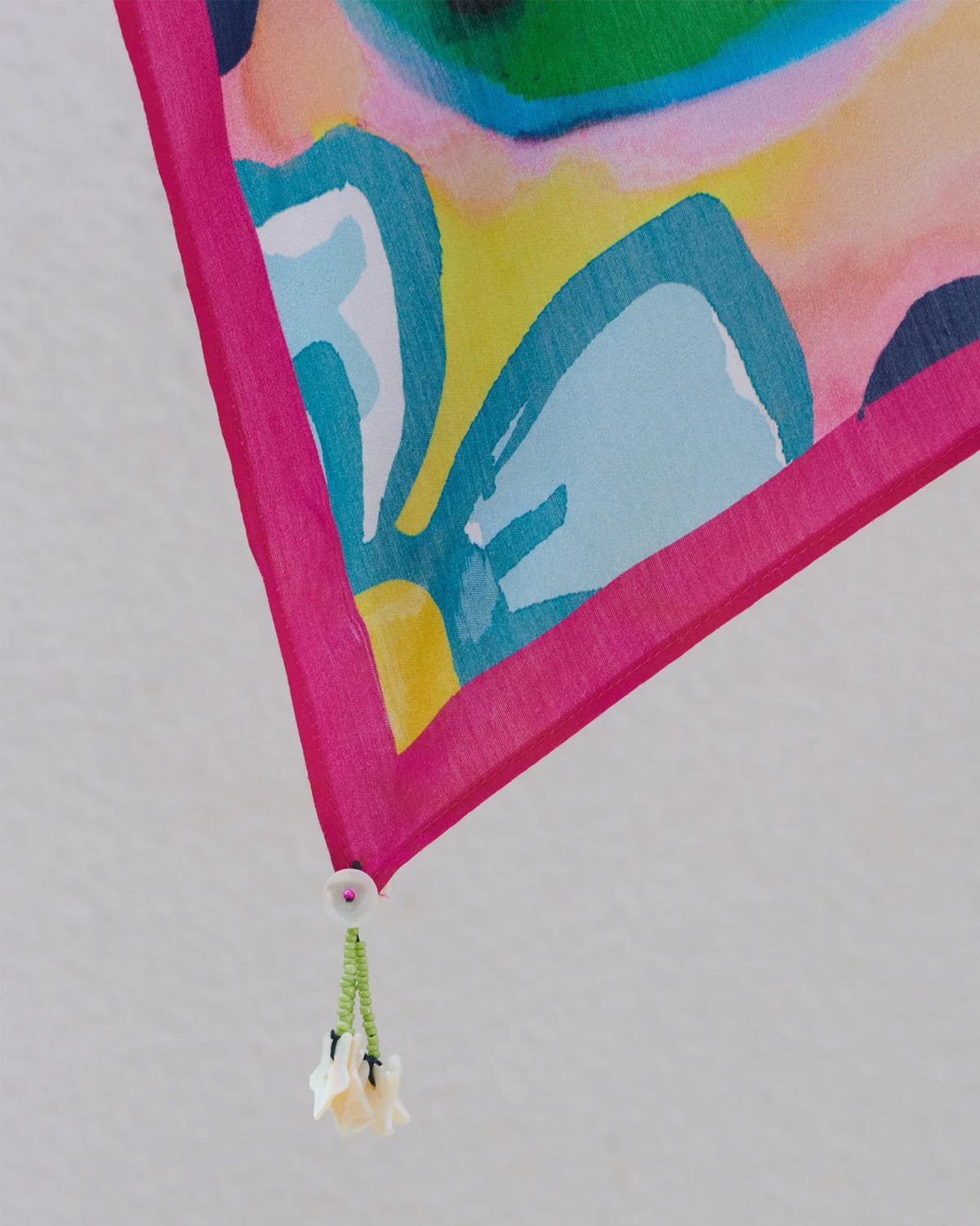 Close-up of a Meadow scarf corner showing blue petals, a pink edge and a white flower tassel.