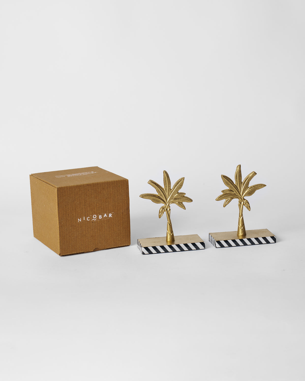 Gilded Palm bookends beside a kraft Nicobar gift box.