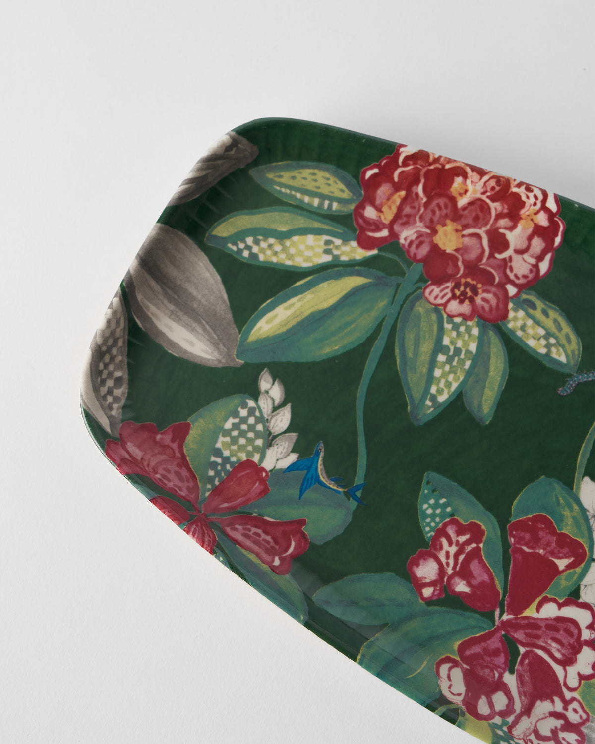 Close-up of Buransh platter florals with checkered leaves and a blue bird.