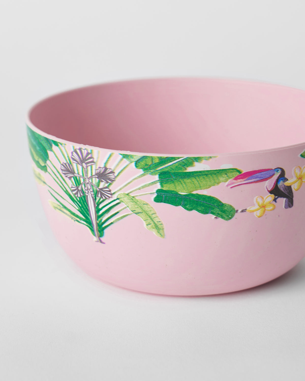 Close-up of a toucan among leaves and flowers on a pink Toucan bamboo cereal bowl.