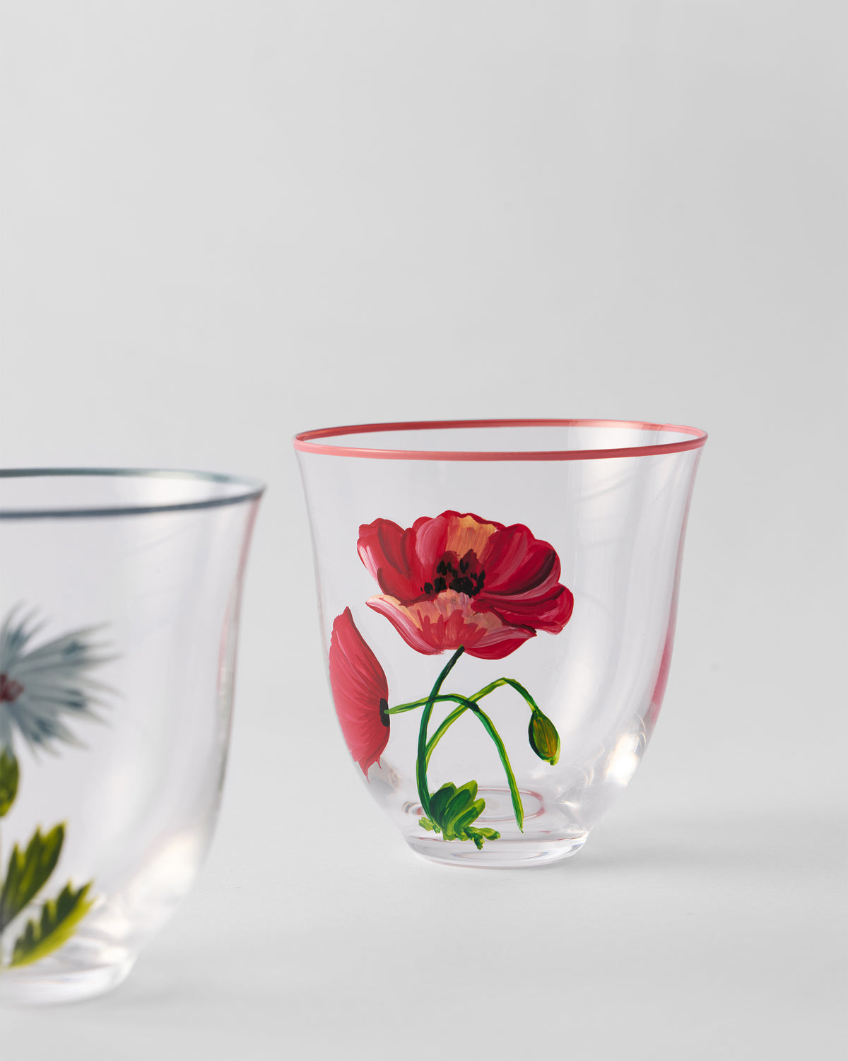 Close-up of a Rit tumbler with a red poppy motif and pink rim.