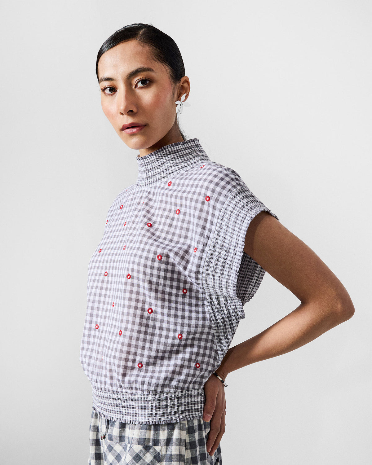 Side view of the Lehar top in grey gingham with a smocked high neck and short cap sleeves.