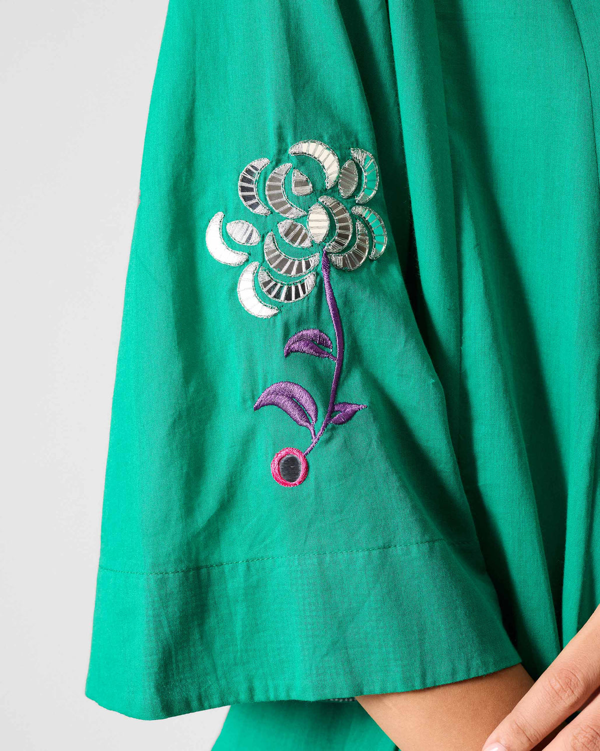 Close-up of a green kurta sleeve with a multicolour embroidered flower.