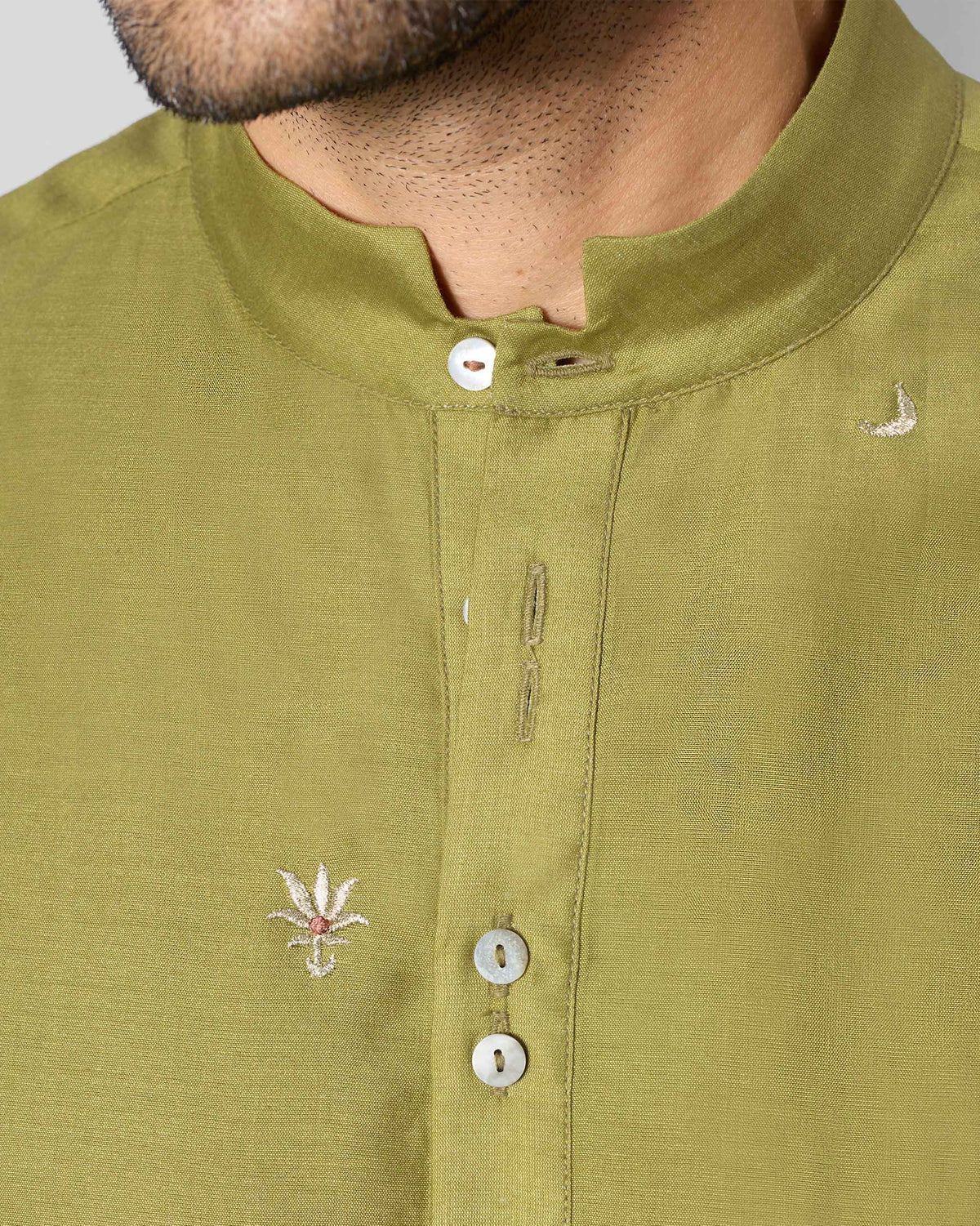 Close-up of an olive Rey kurta collar with small embroidered motifs.