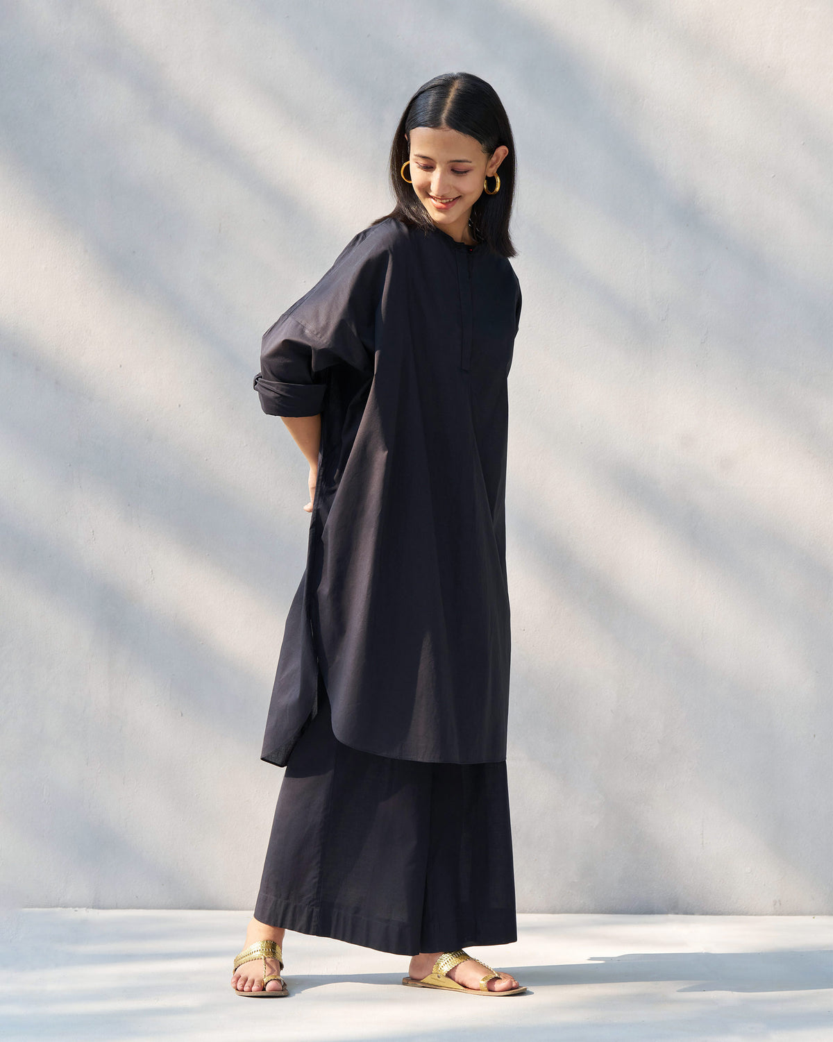 Side view of a black Lazy Sunday tunic with a curved hem.