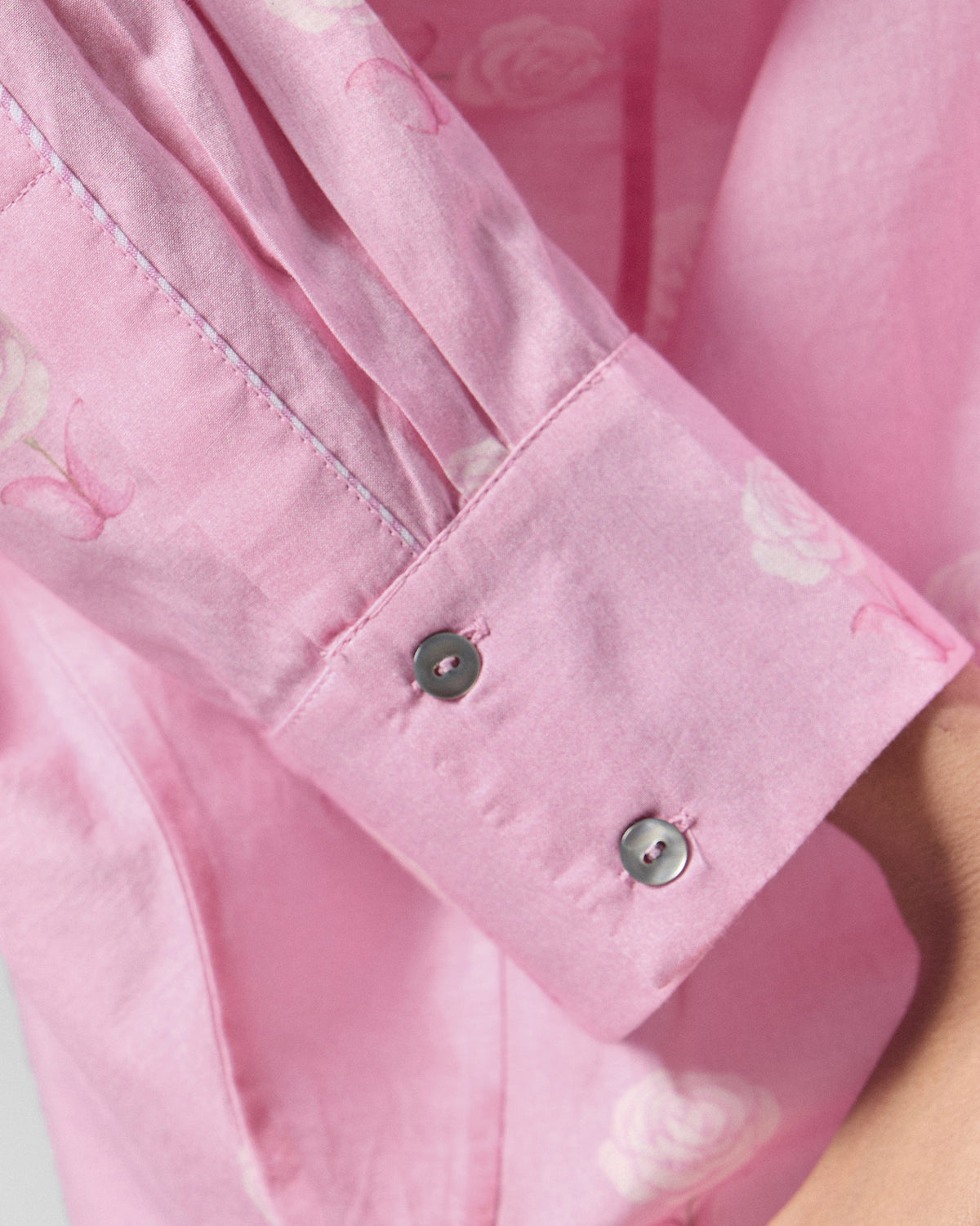 Close-up of a buttoned cuff on a pink floral tunic.