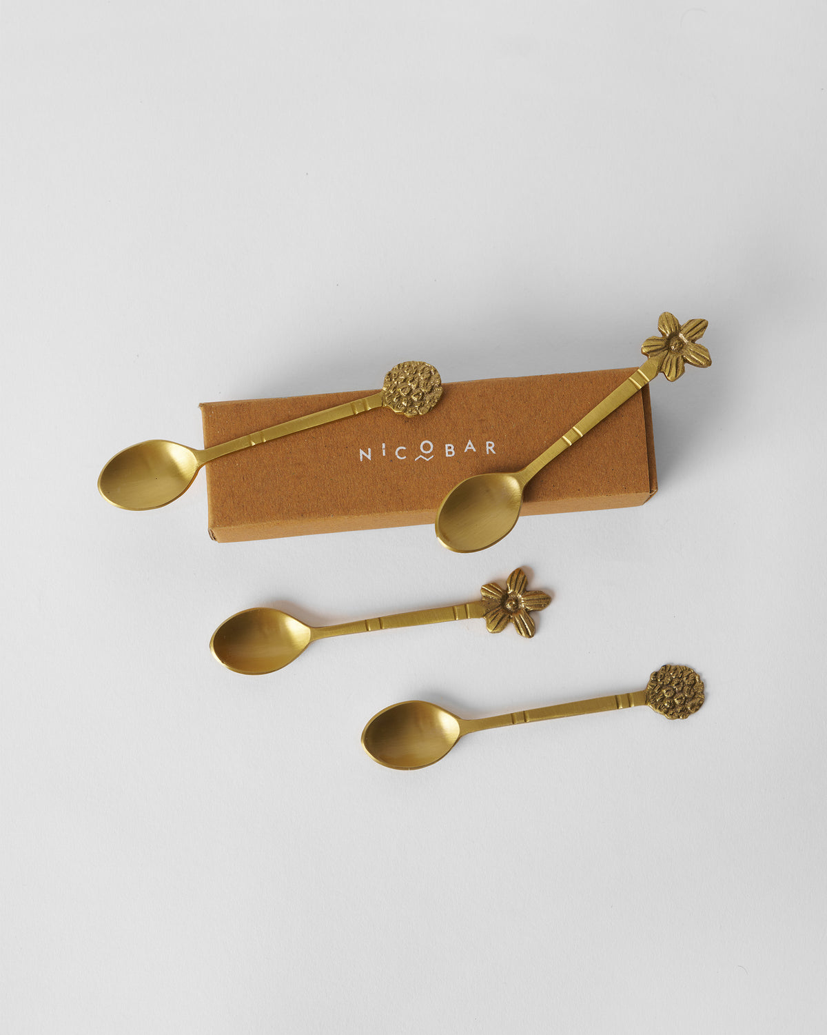Gold Bloom Coffee Spoon set of four in front of a Nicobar box.