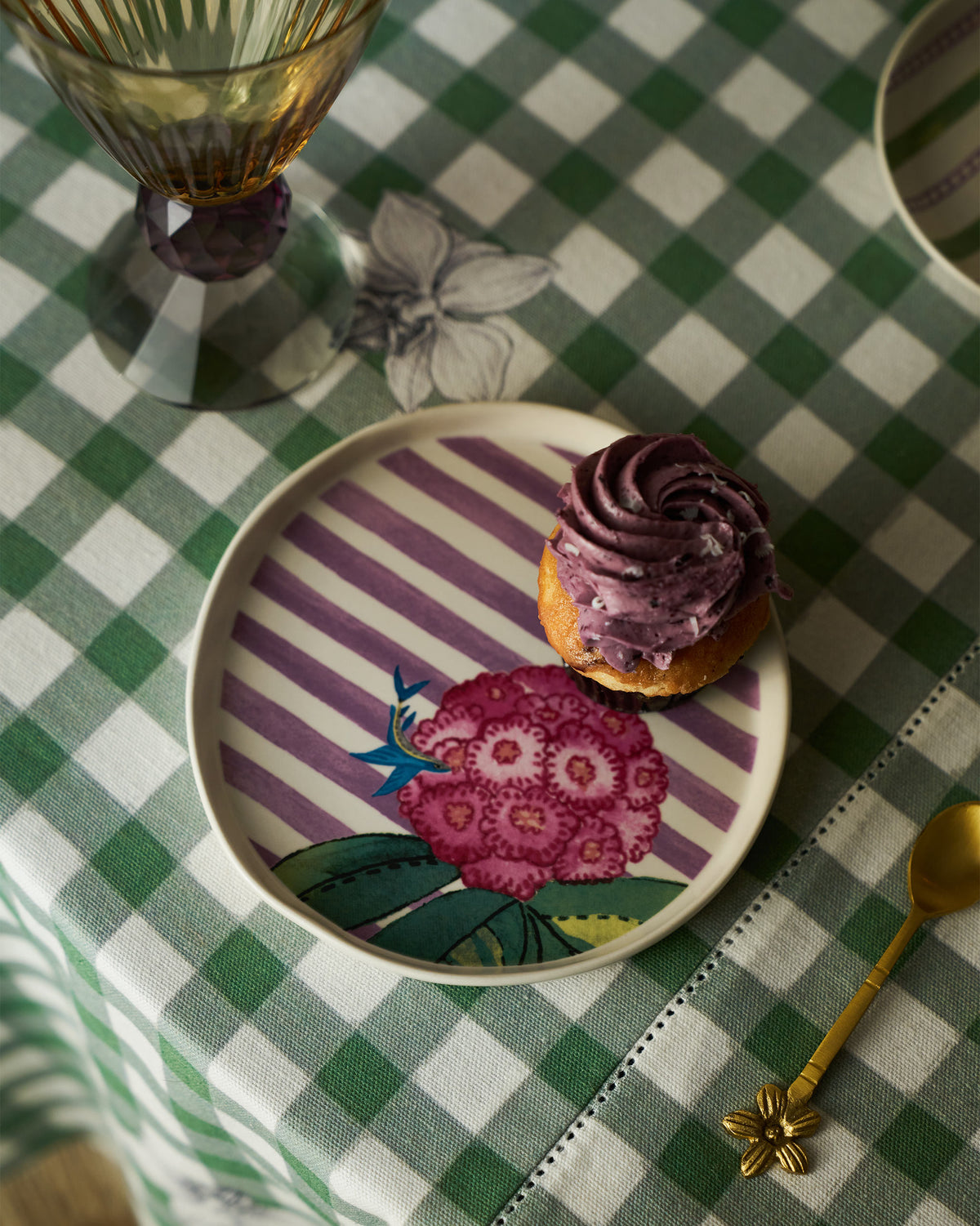 Buransh dessert plate with a cupcake and gold spoon on a gingham cloth.