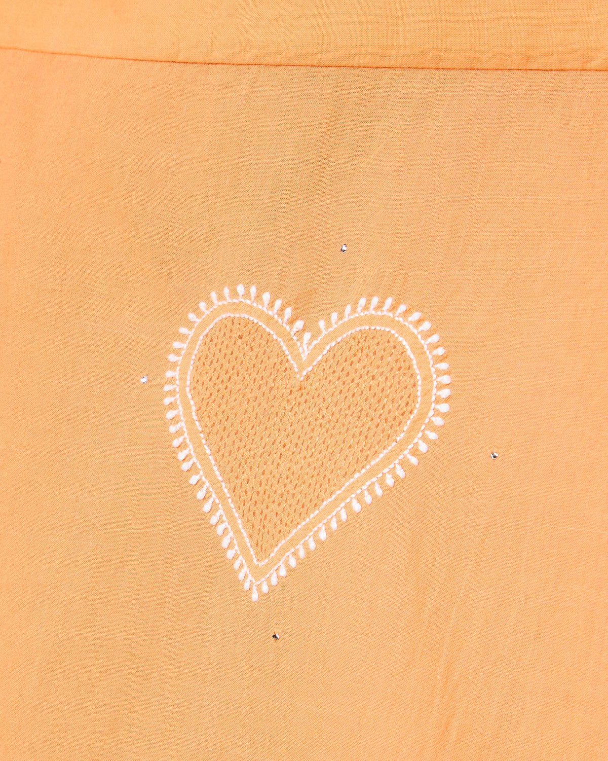 Close-up of an embroidered heart motif on peach fabric from the Lazy Sunday set.