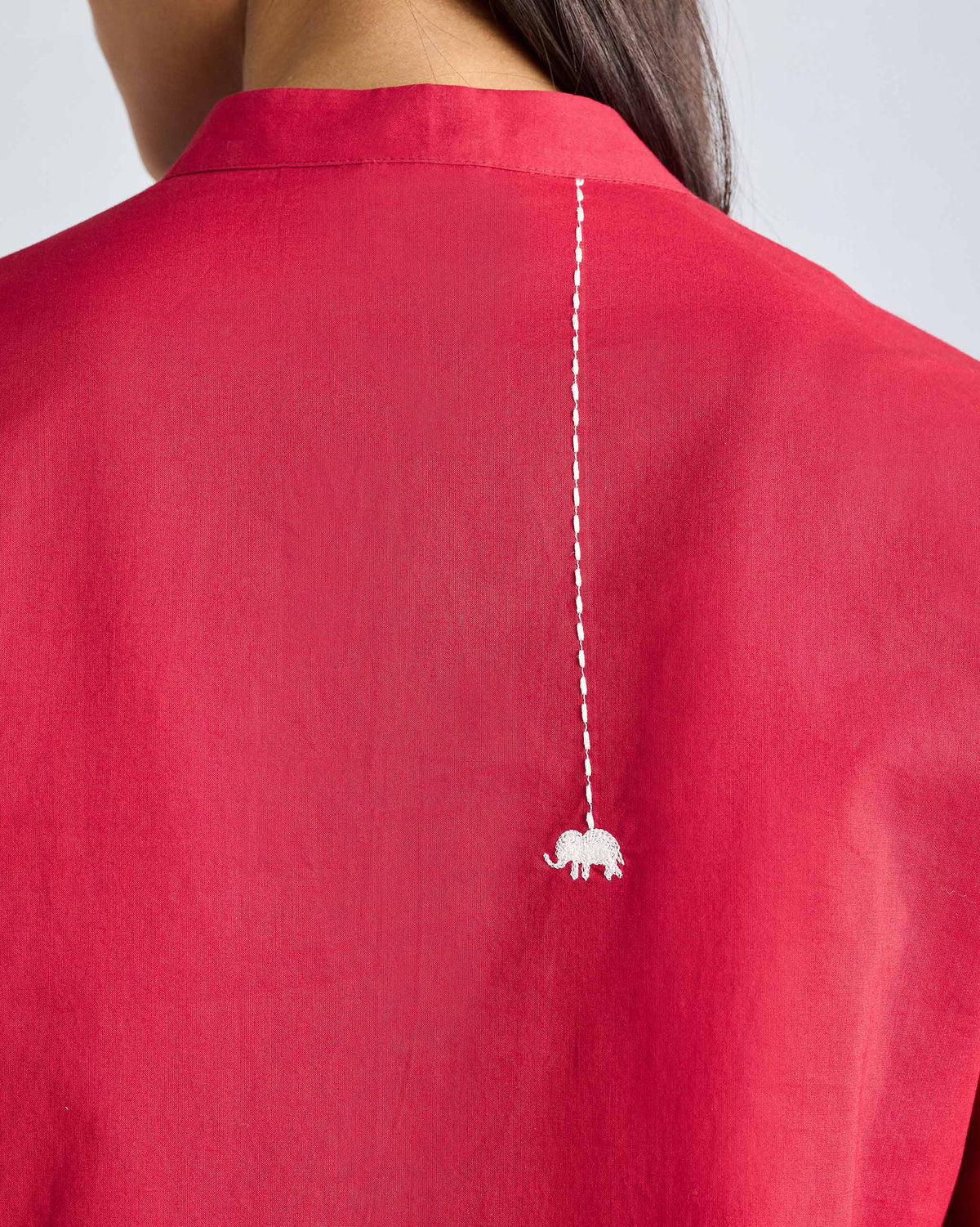 Close-up of a white elephant embroidery on the back of a red kurta.