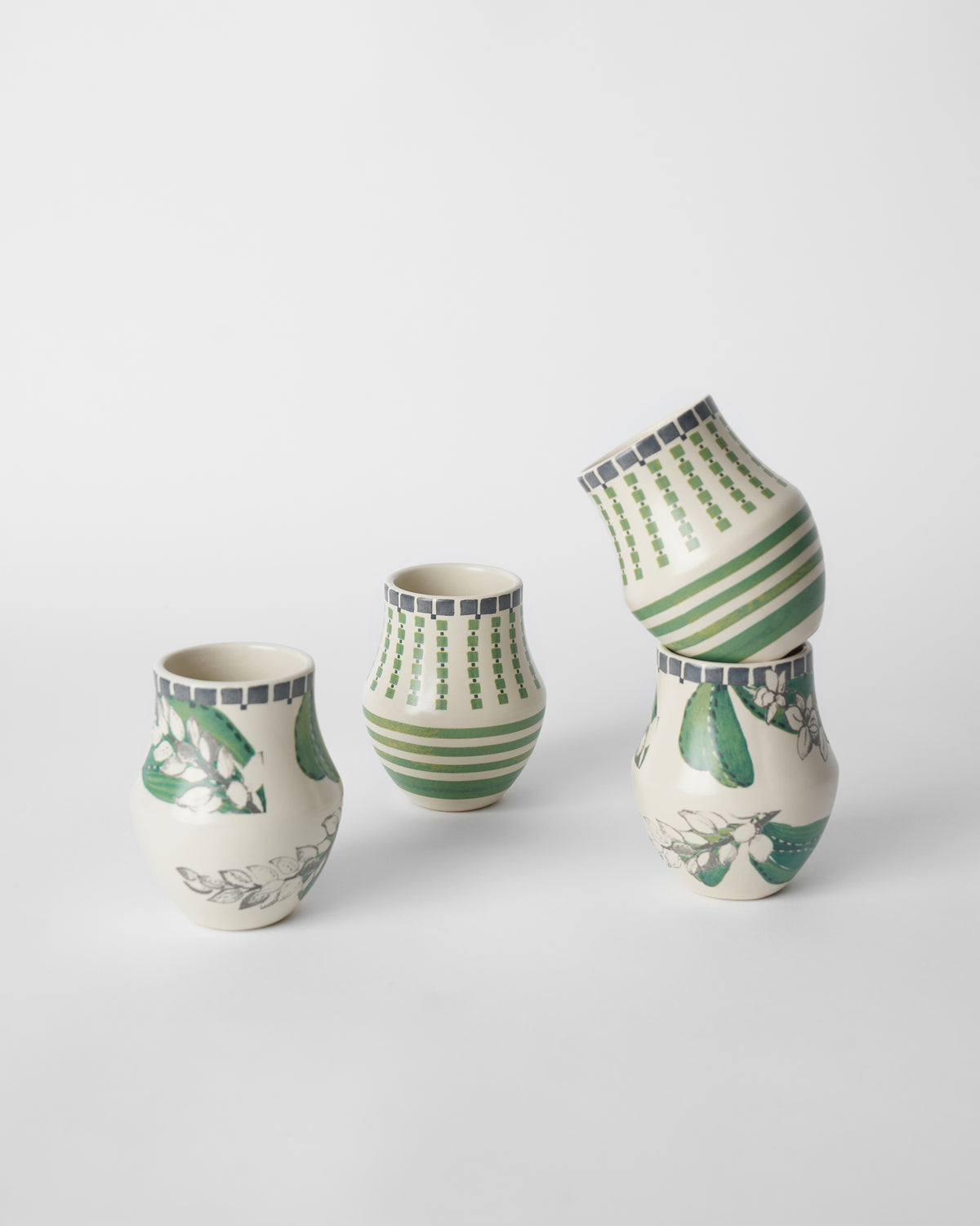 Set of four Reesha kulhars with green floral and geometric stripe designs.