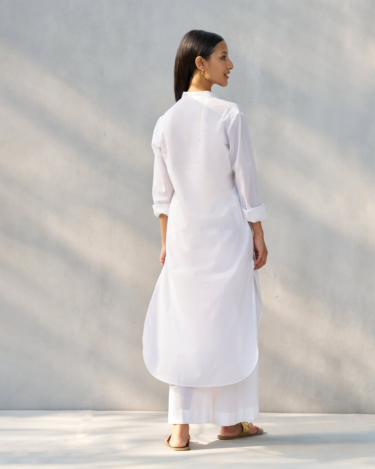 Back of a white long kurta set with a deep curved hem.