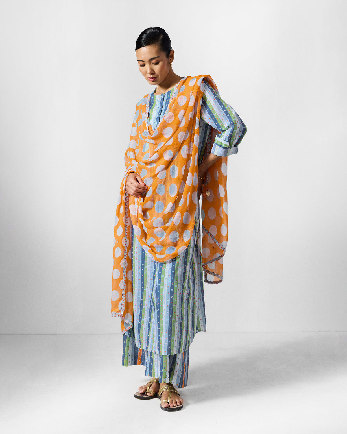 Person wearing the Imke kurta set with an orange dupatta printed with white dots.
