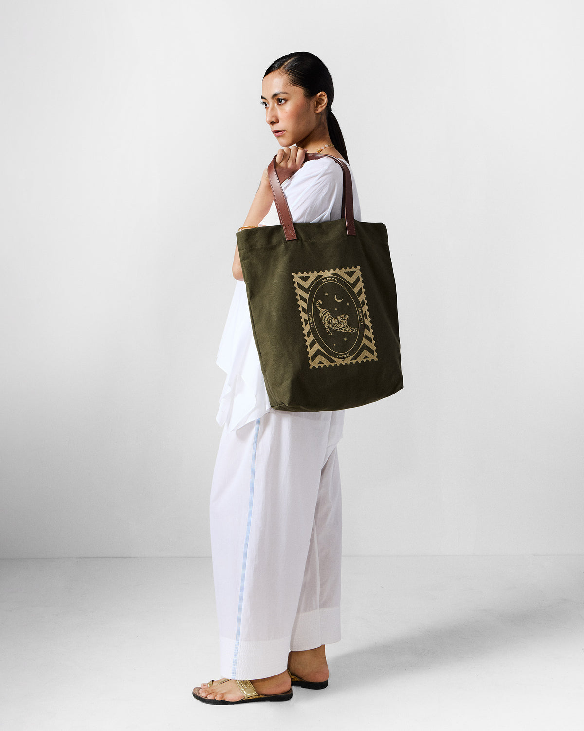 Person wearing an ivory Riva top set with an olive tote bag.