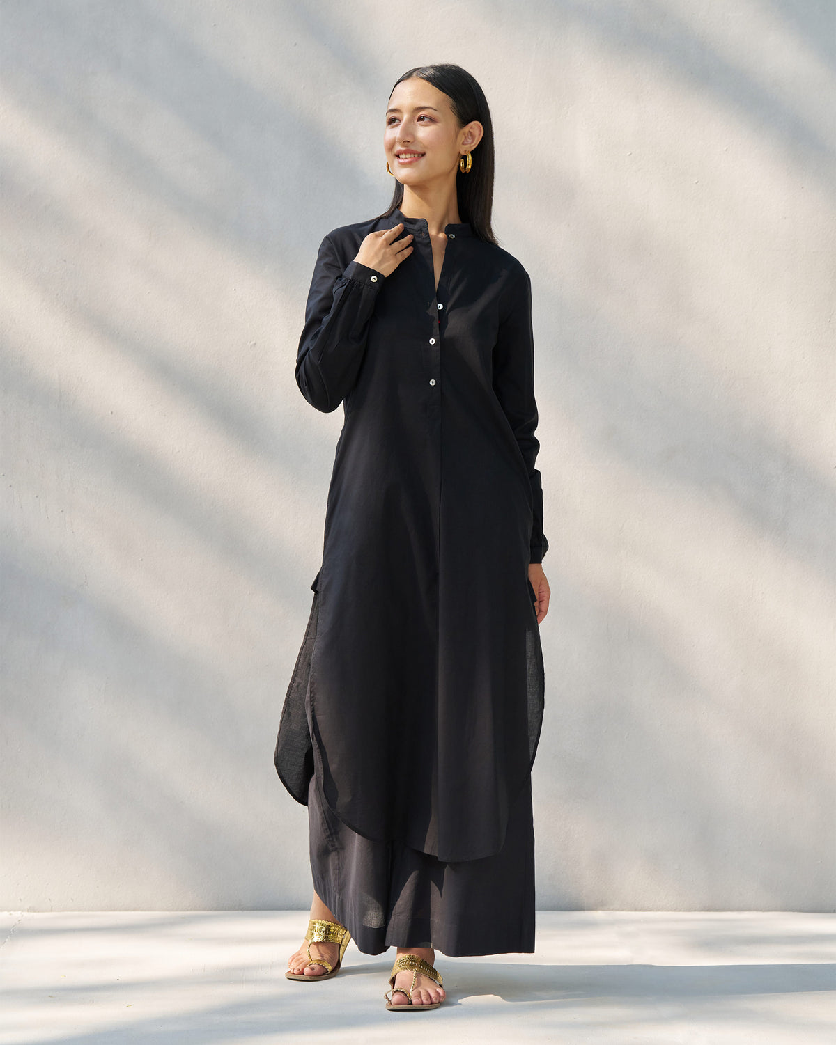 Person wearing a black long kurta set with a button placket.