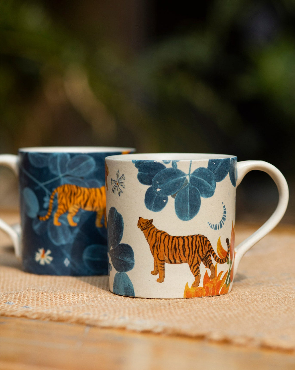Pair of Nadi mugs in cream and navy with matching tiger and leaf prints.