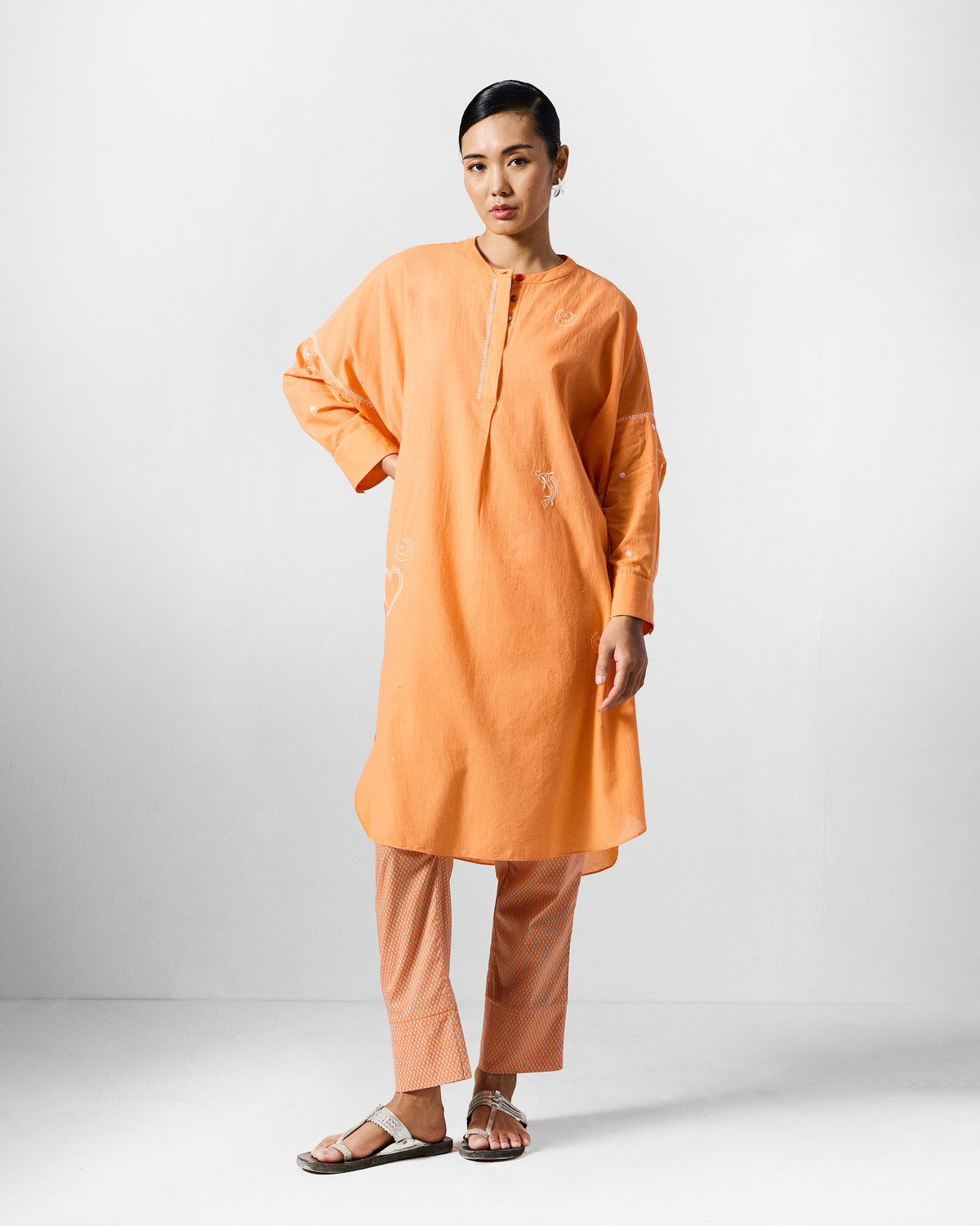 Person wearing an orange Lazy Sunday Tunic Set with white heart embroidery.