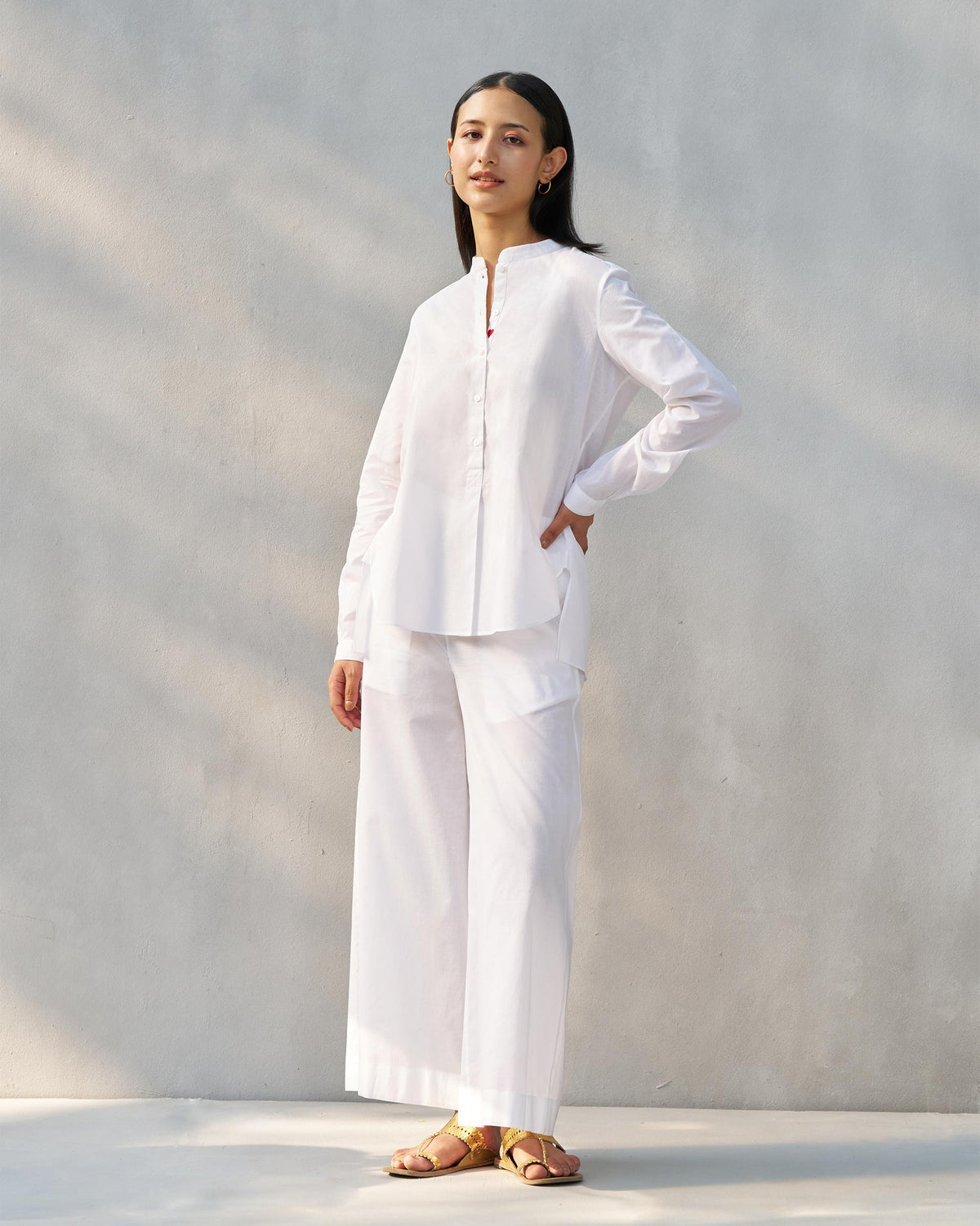 Person wearing a white mandarin collar top set with matching wide-leg pants.