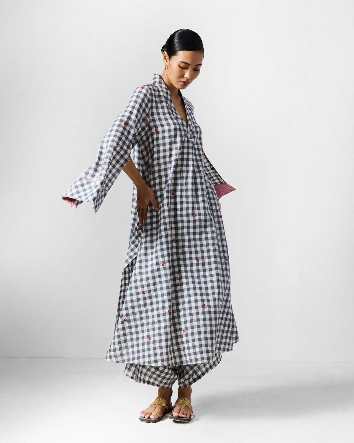 Grey and white check kurta set with hands in pockets and pink cuff lining.