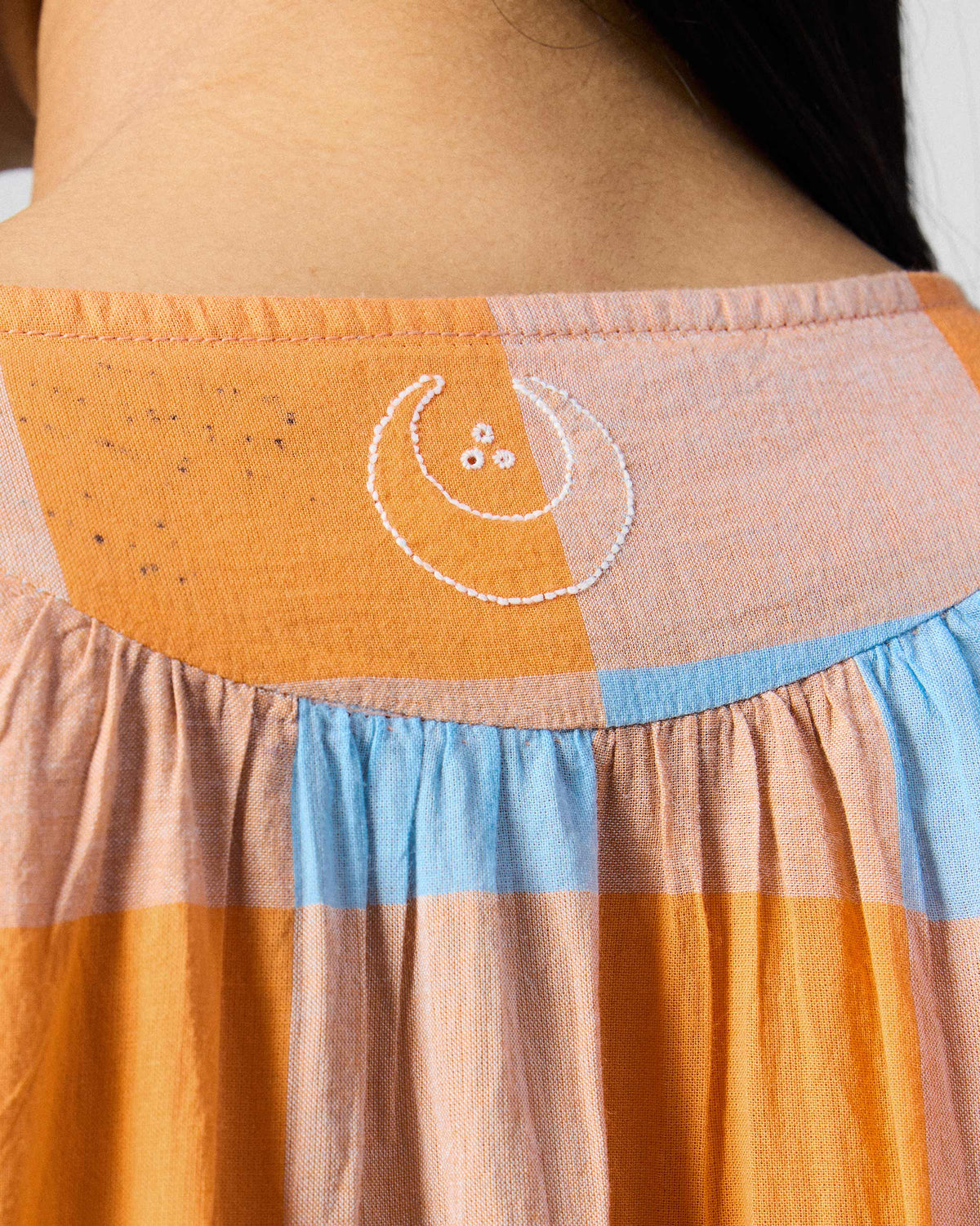 Close-up of white embroidery on the back yoke of a Vaya kaftan.