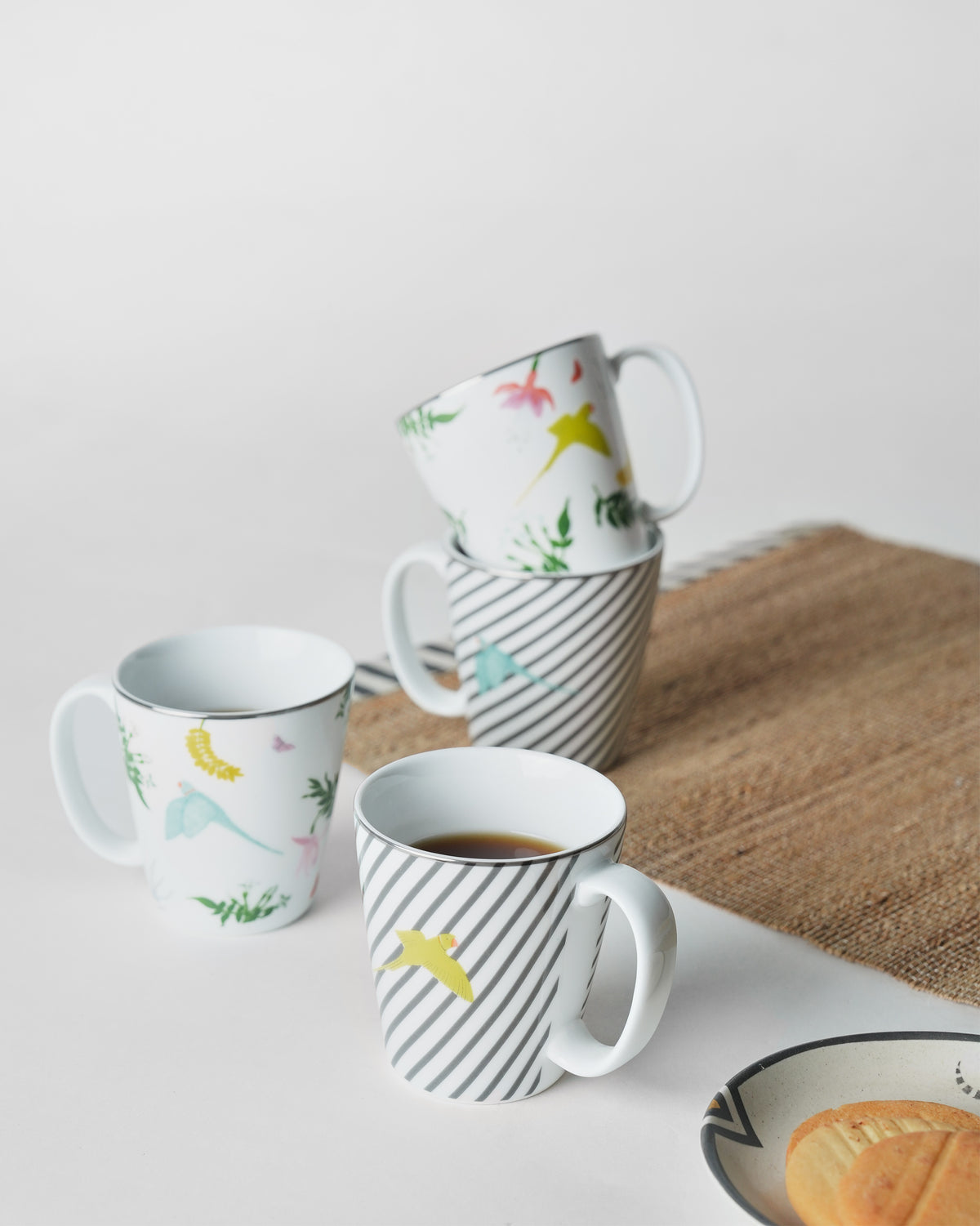 Botanical Coffee Mugs on a table with coffee and biscuits.