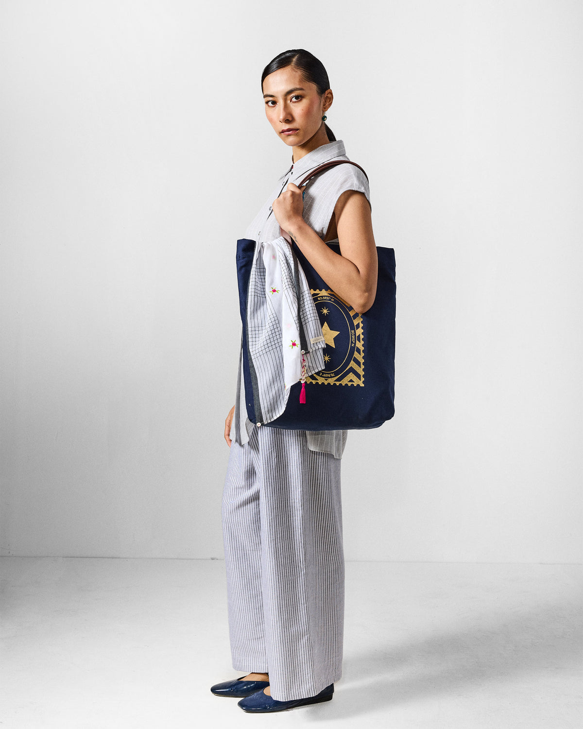 Person wearing a grey and white striped Rin Top Set with a navy tote.