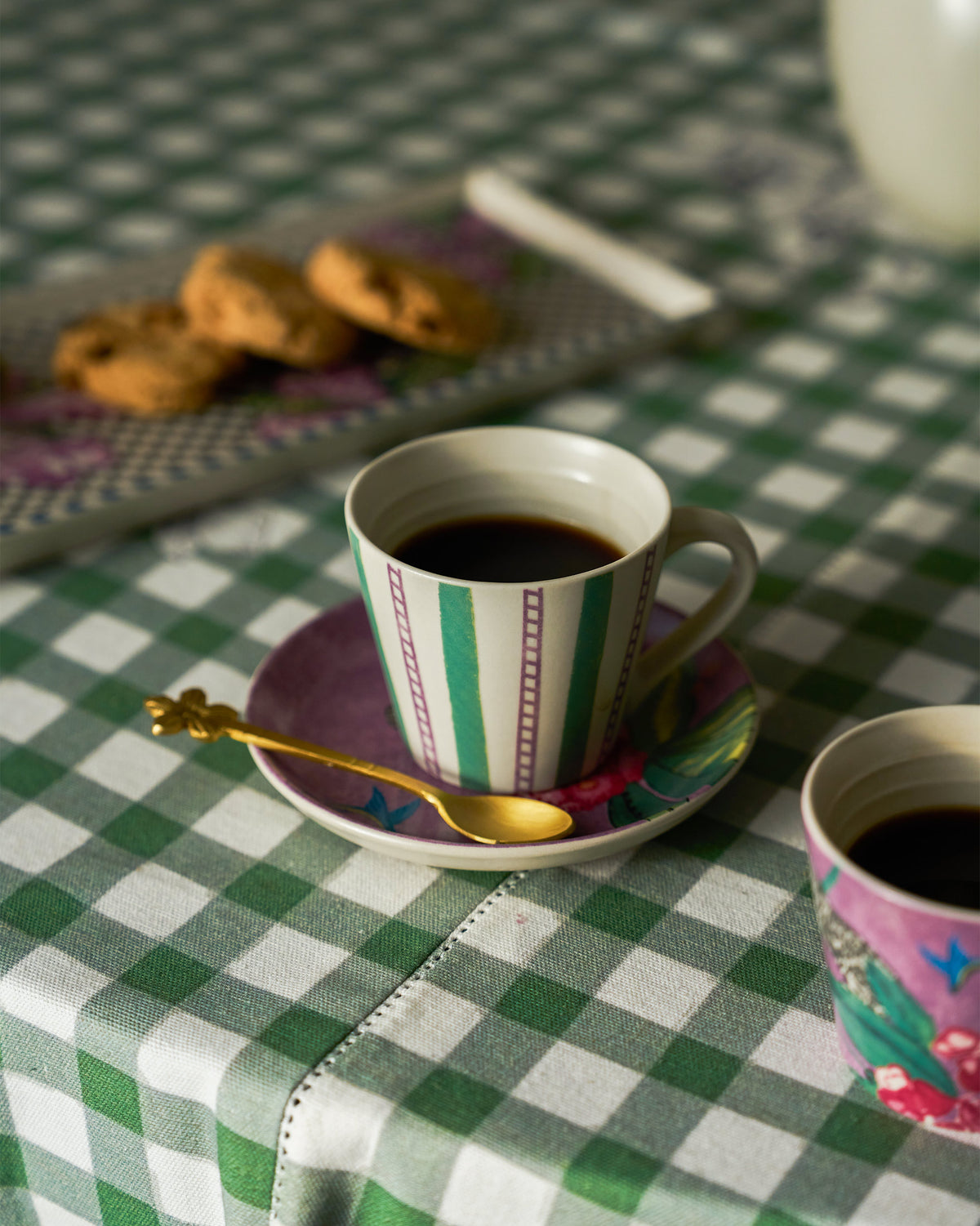 Striped Buransh Espresso Mug filled with coffee on a floral saucer.