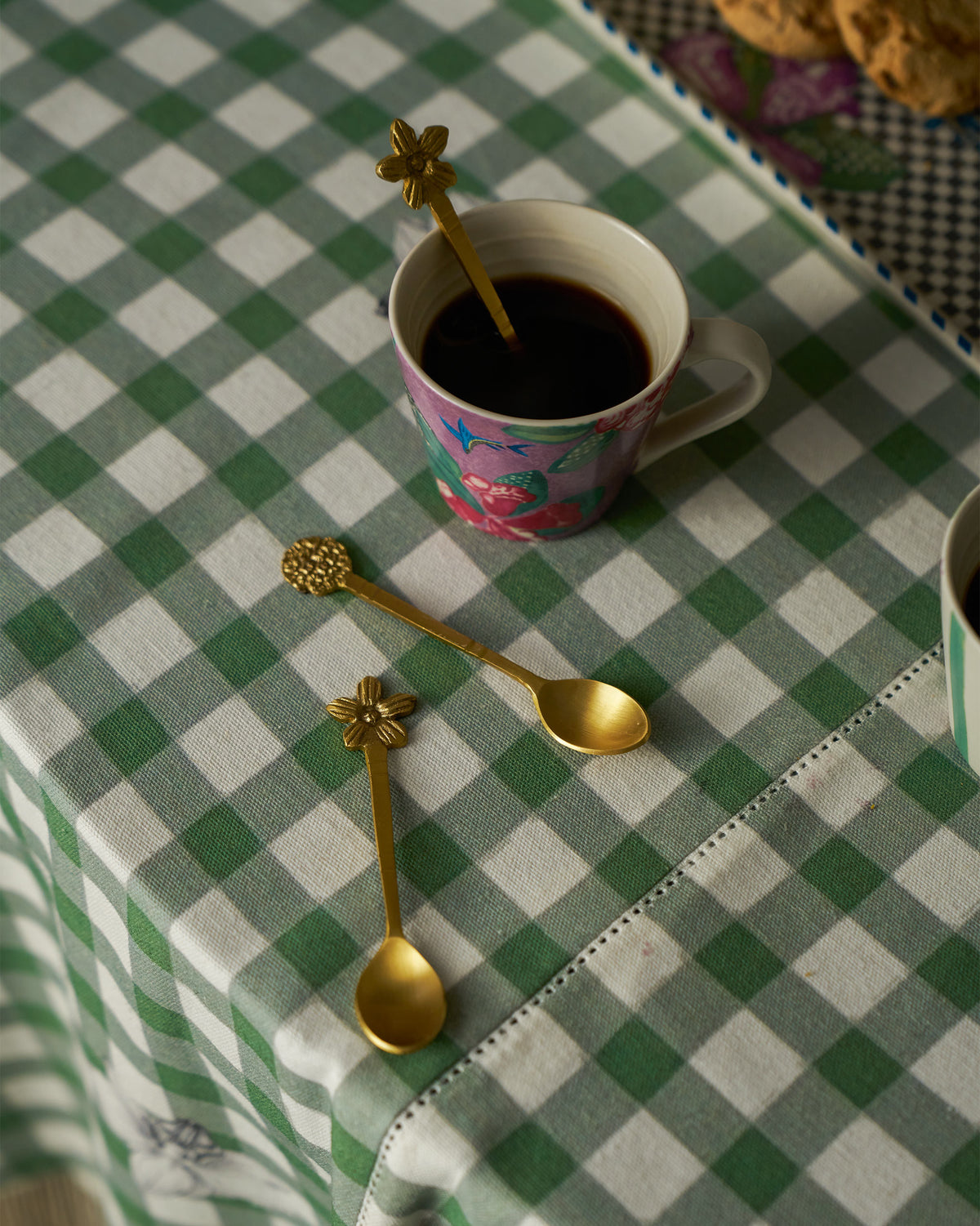 Gold Bloom Coffee Spoons resting with a floral mug of coffee.