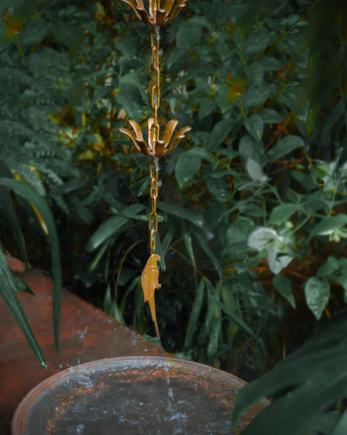 Madagascar Rain Chain with a parrot pendant hanging over a basin.