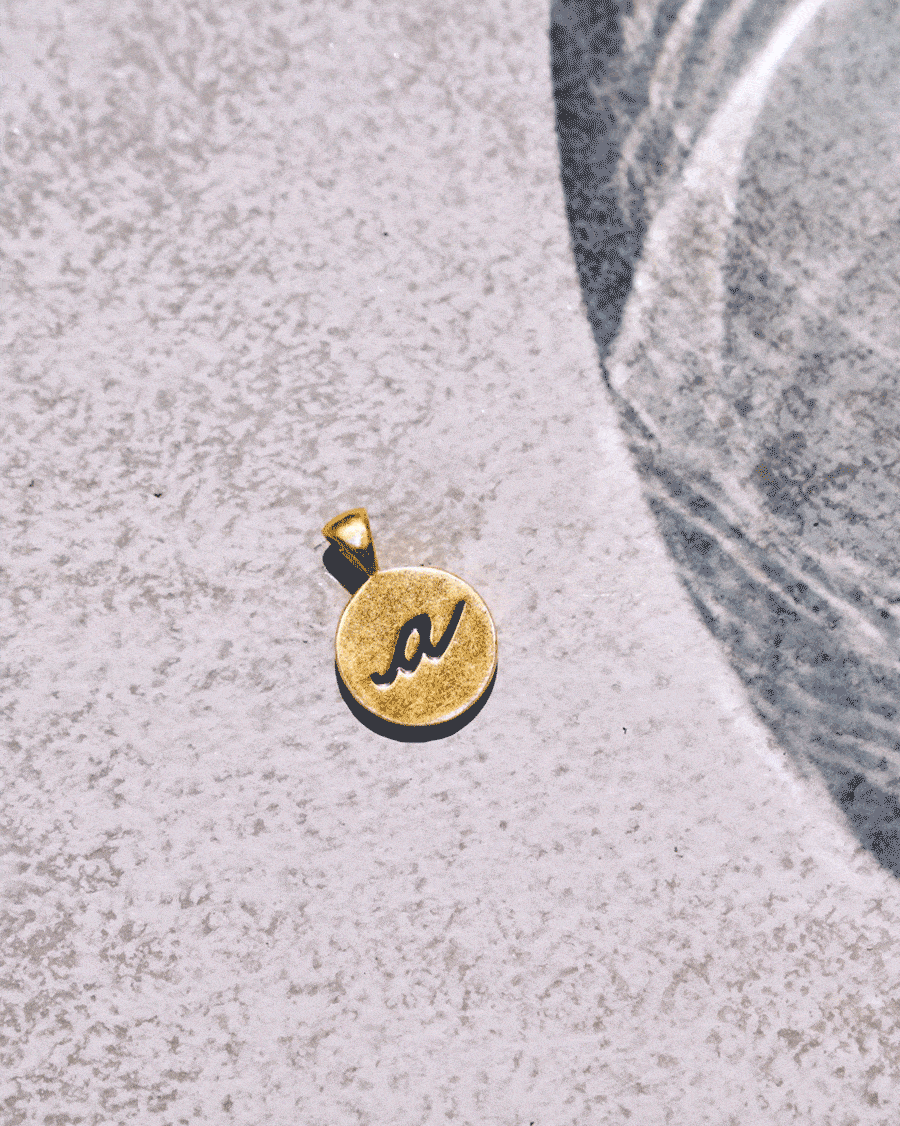 Gold alphabet charm GIF looping letter faces on stone.