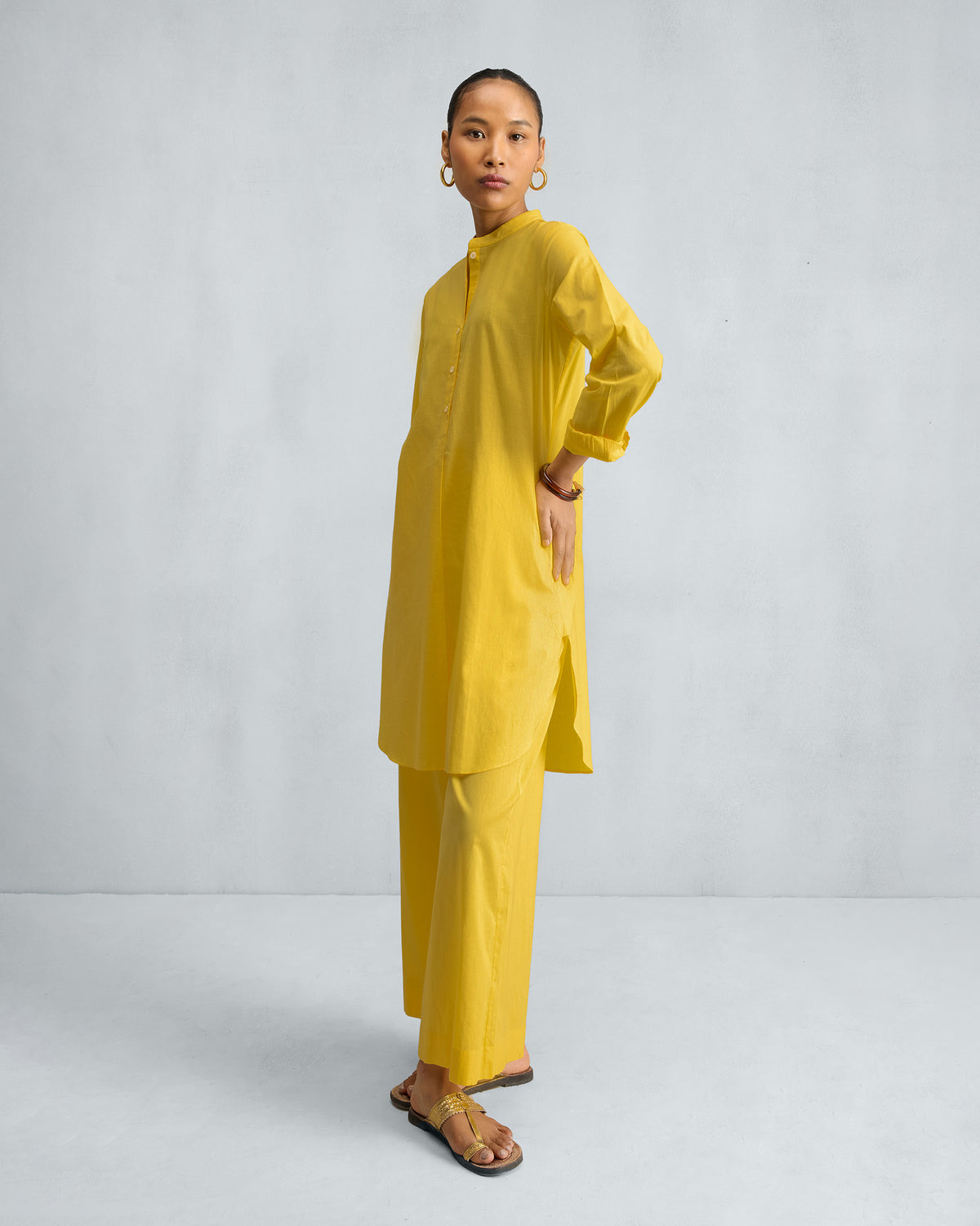 Yellow mid-length kurta set with a mandarin collar and matching trousers.