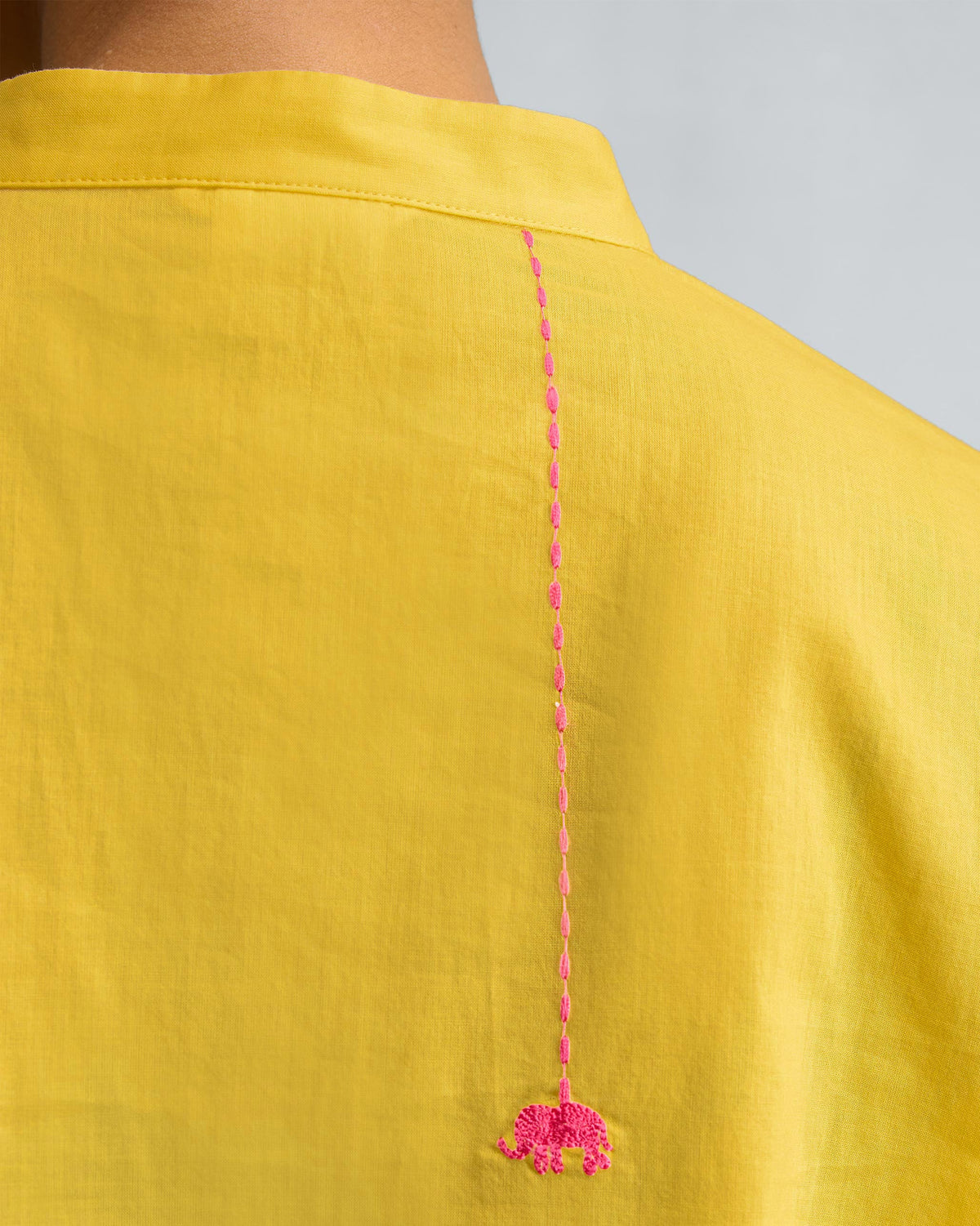 Close-up of a pink elephant embroidery on the back of a yellow kurta.