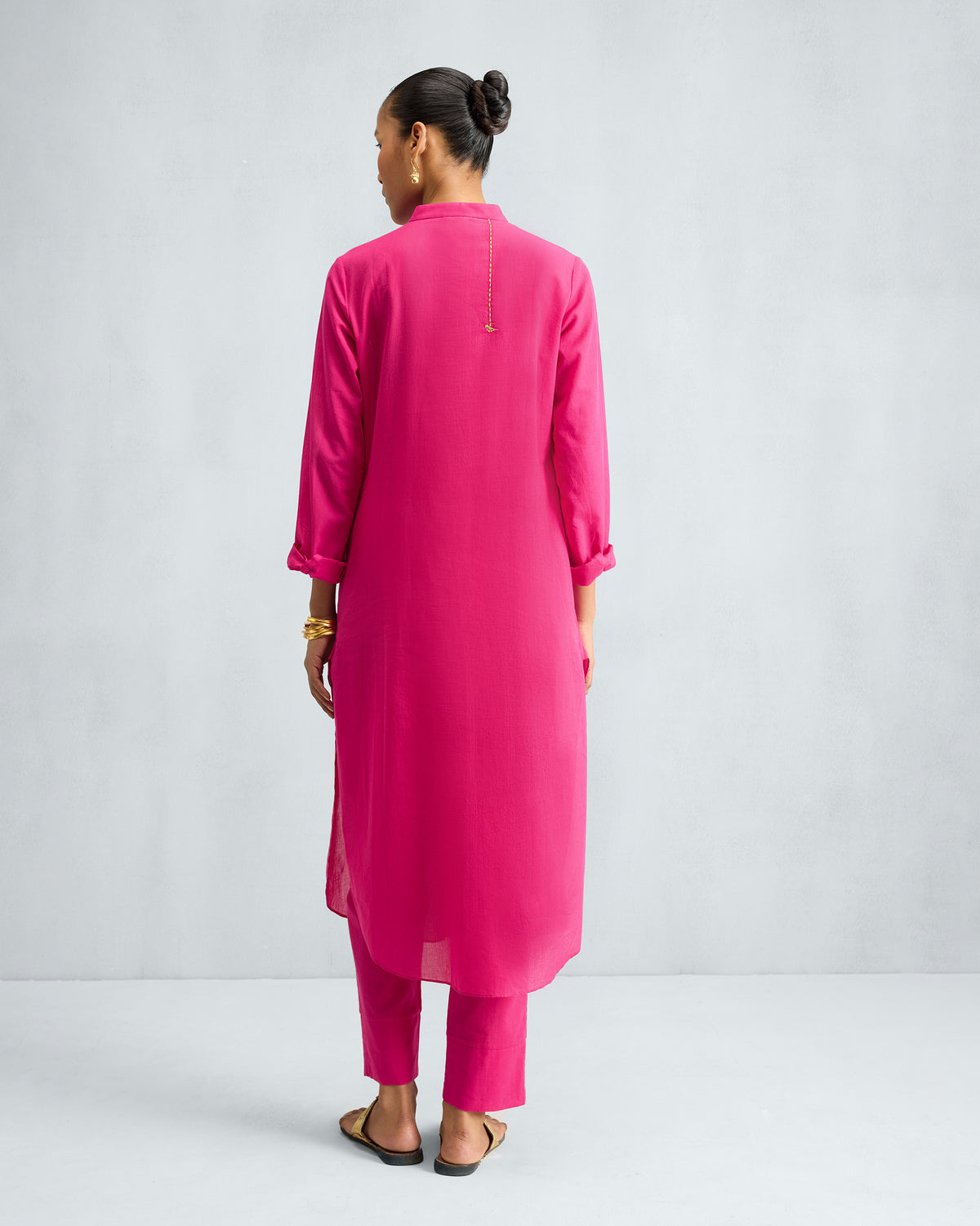 Back of a fuchsia long kurta worn with matching trousers.