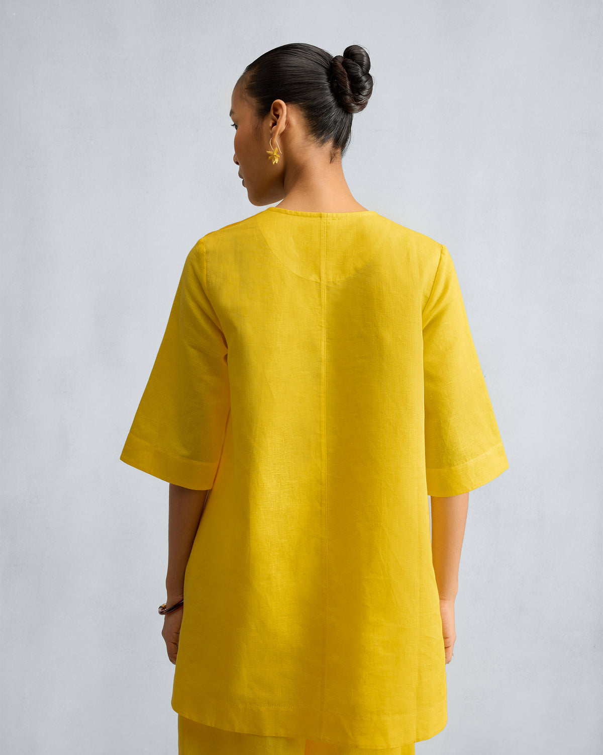 Back of a yellow high slit top with matching wide-leg pants.
