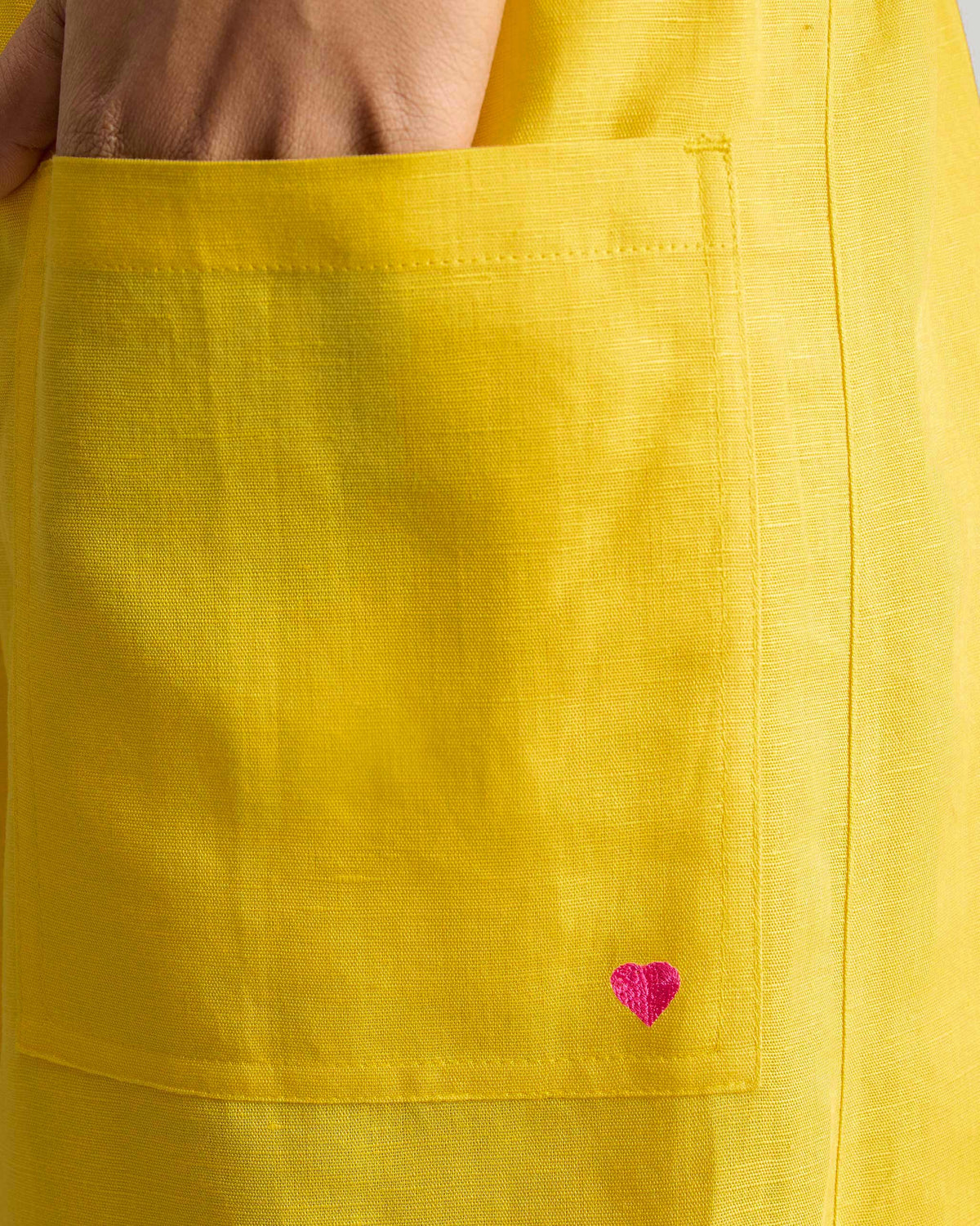 Close-up of a pink heart on a yellow patch pocket.