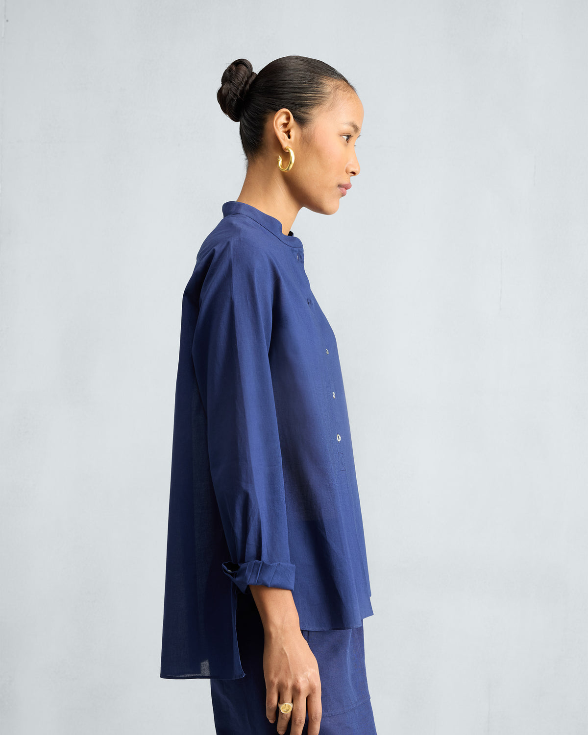 Side view of an ink blue mandarin collar top with a high-low hem.