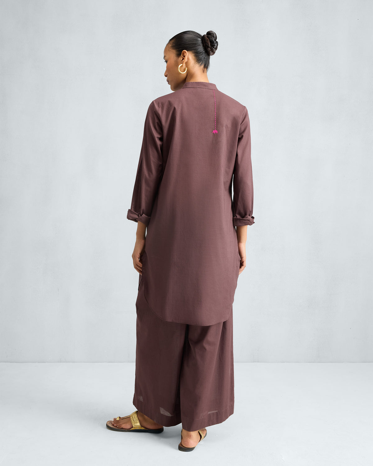 Back of a chocolate plum mid-length kurta set with a curved hem.