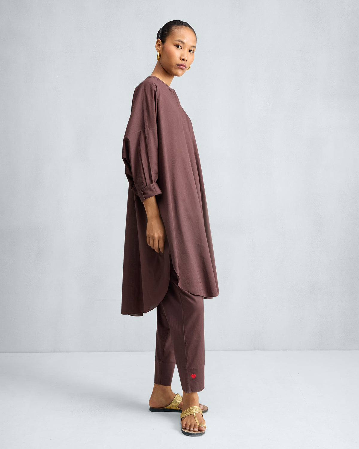 Side view of a chocolate plum Lazy Sunday tunic set with a high-low hem.