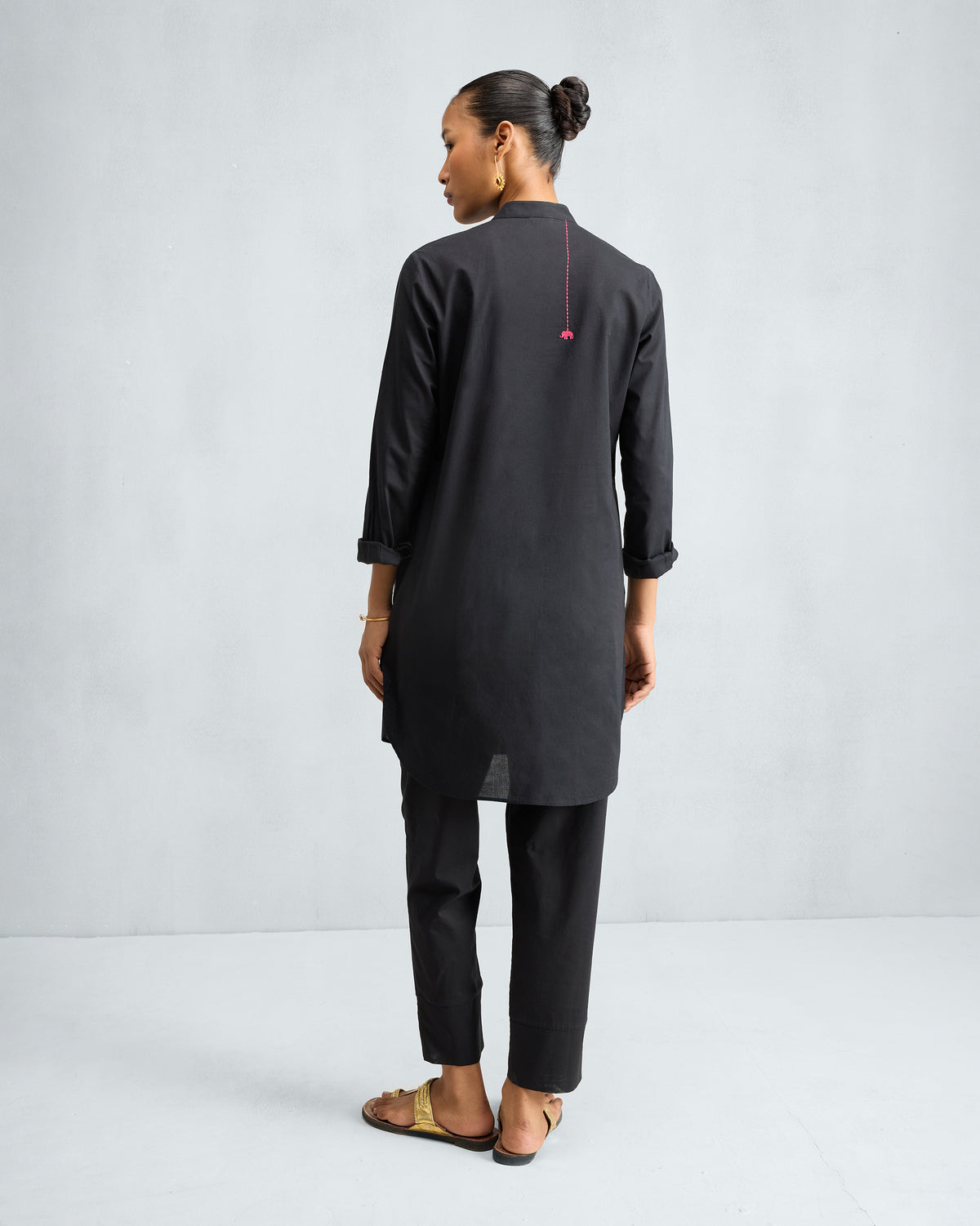 Back of a black mid-length kurta with a pink elephant embroidery.
